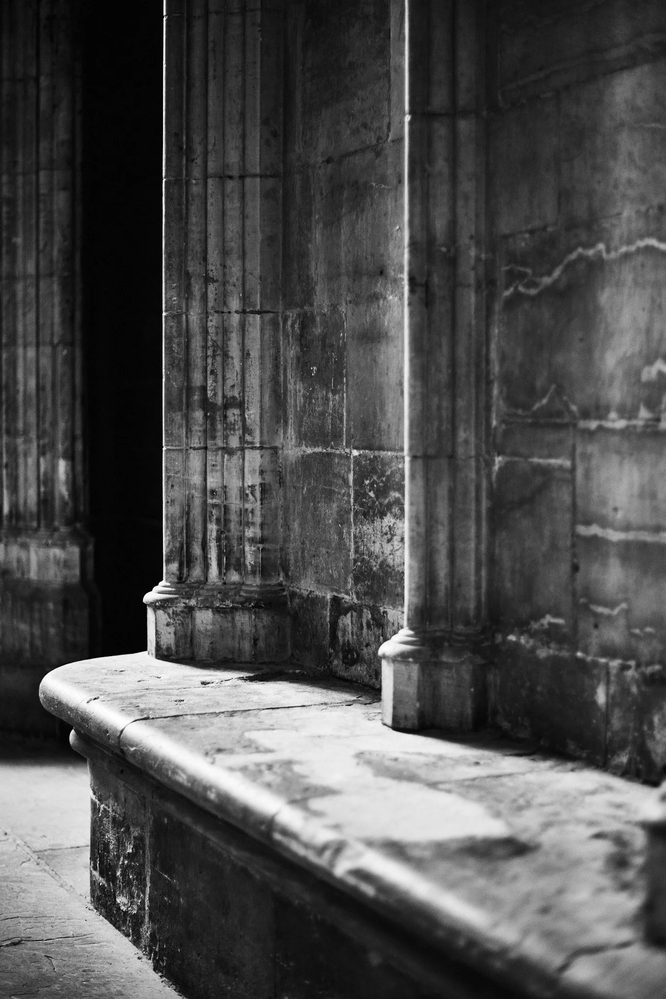 Close-up of weathered stone columns and a curved stone bench inside York Minster.