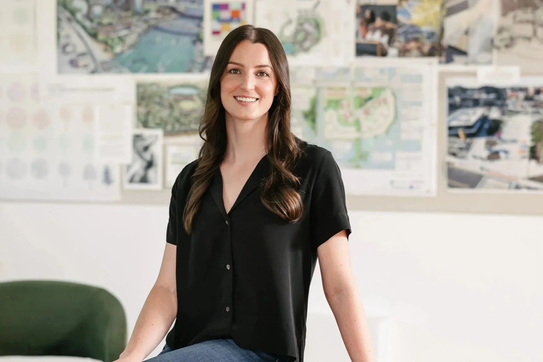 Emma Swanson standing in front of a wall with various maps and architectural plans.