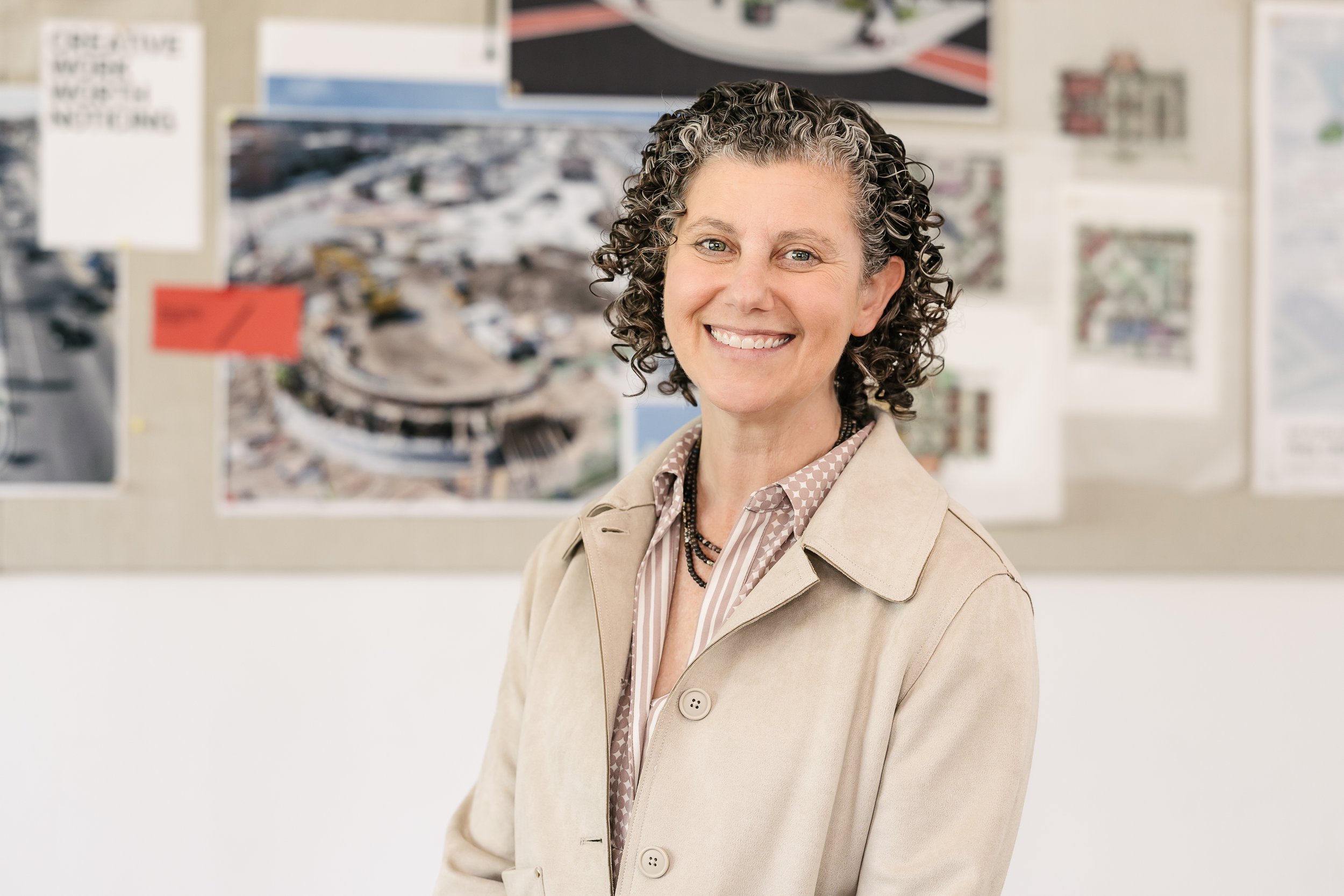 Jodi Mariano stands in front of a wall with various colorful posters and images.