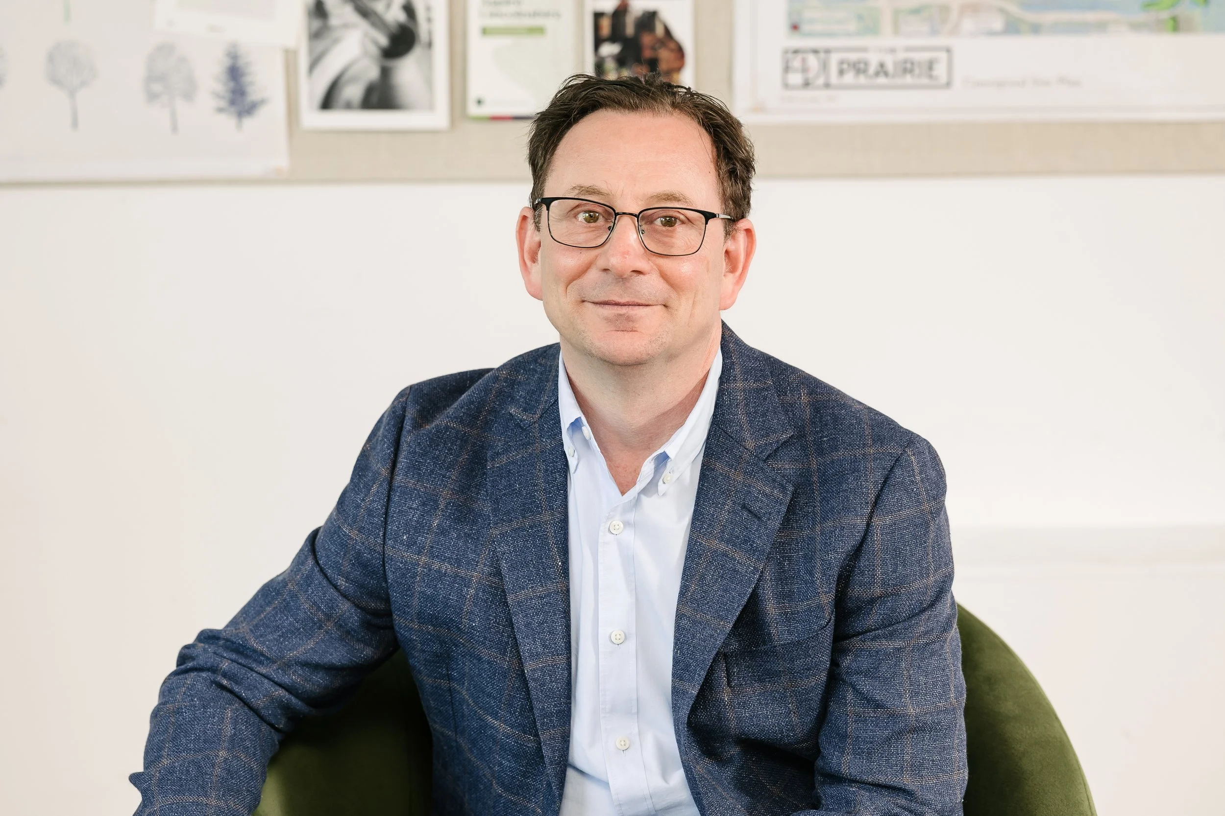 Scott Golstein sitting on a green chair in an office, smiling.