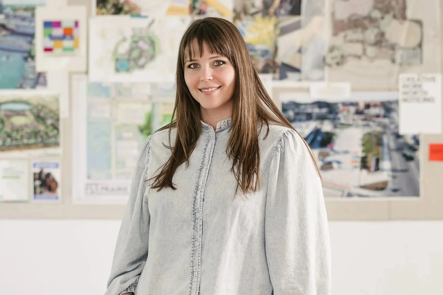 Lacey Carlson standing in front of a bulletin board filled with maps, photographs, and notes.