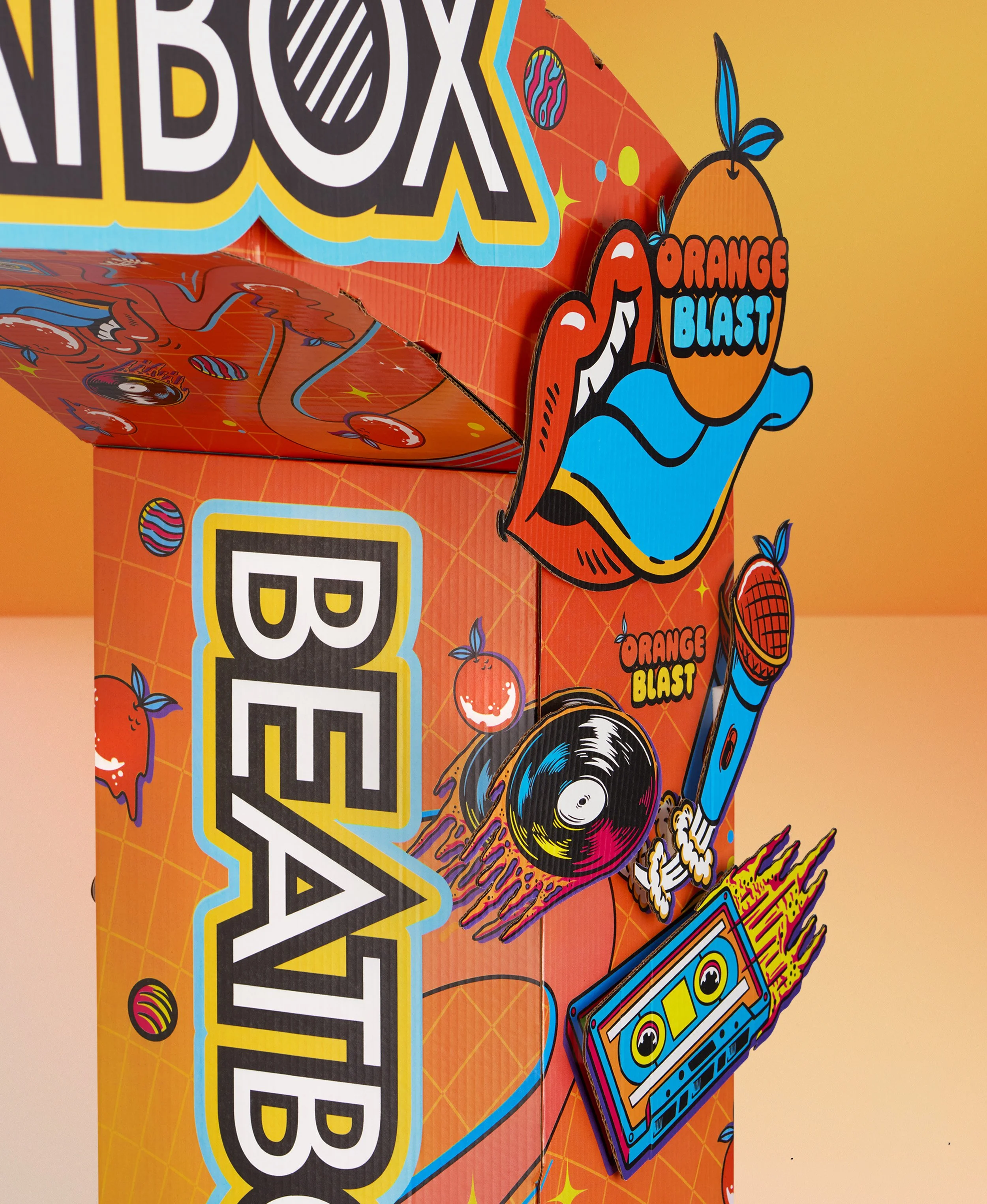 Colorful packaging for a product called "Orange Blast" featuring vibrant cartoon-style graphics including a smiling orange, a cassette tape, vinyl records, and abstract geometric designs in bright colors.