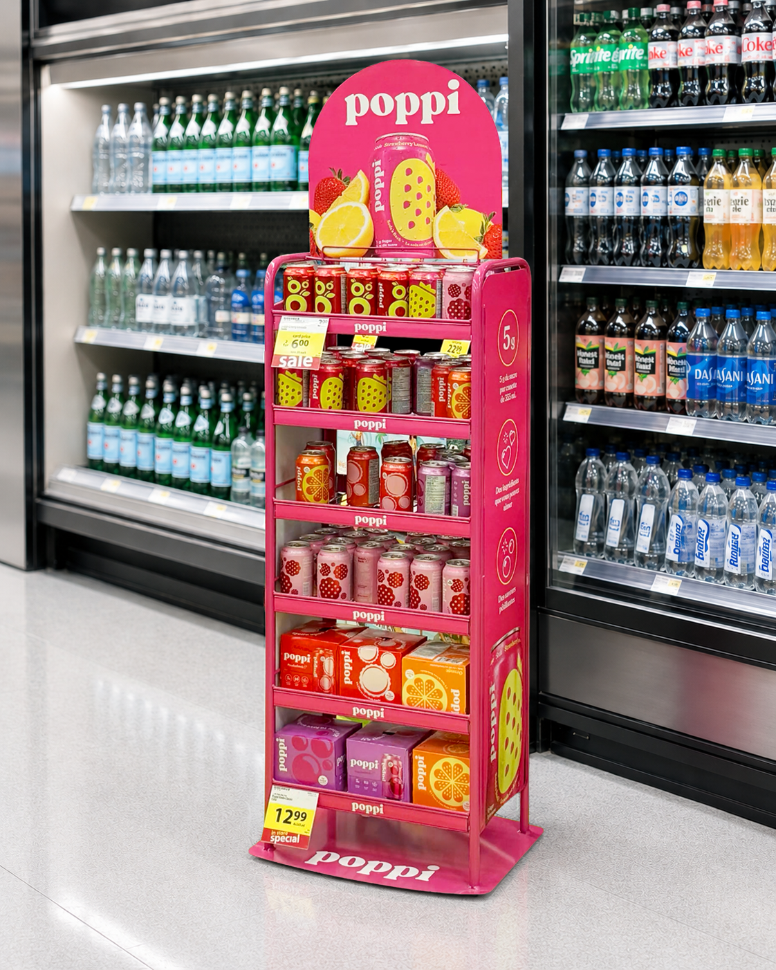 Pink poppi floor display stocked with cans and multipacks beside a grocery beverage cooler
