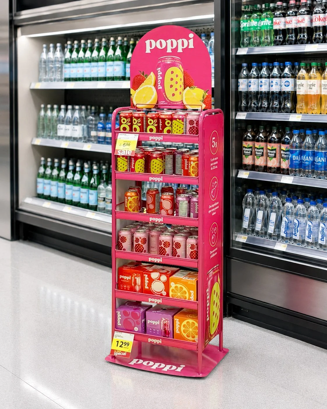Pink poppi floor display stocked with cans and multipacks beside a grocery beverage cooler