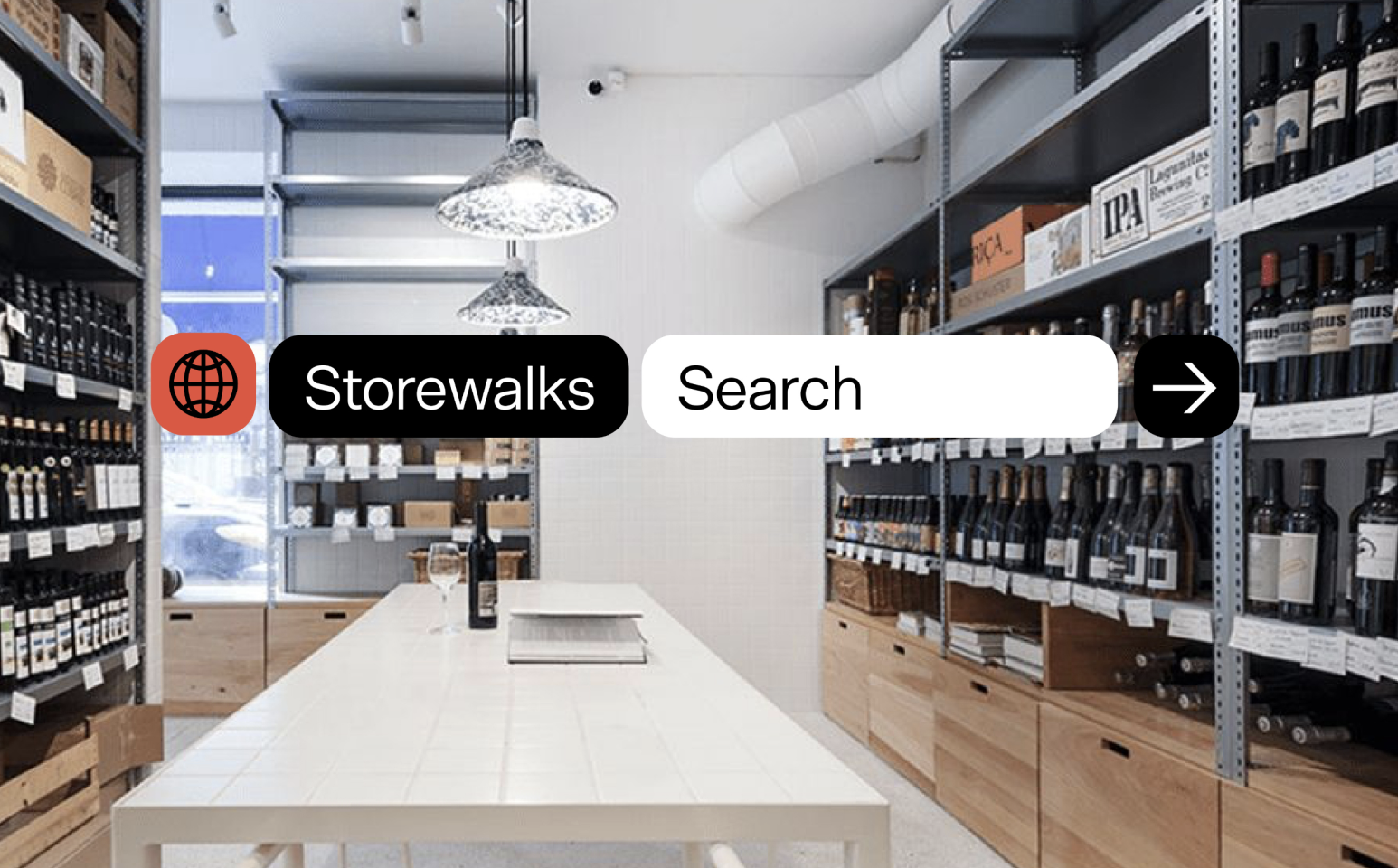 Interior of a wine shop with shelves filled with wine bottles, a white dining table with a wine bottle and glass, wooden drawers, and pendant lighting.
