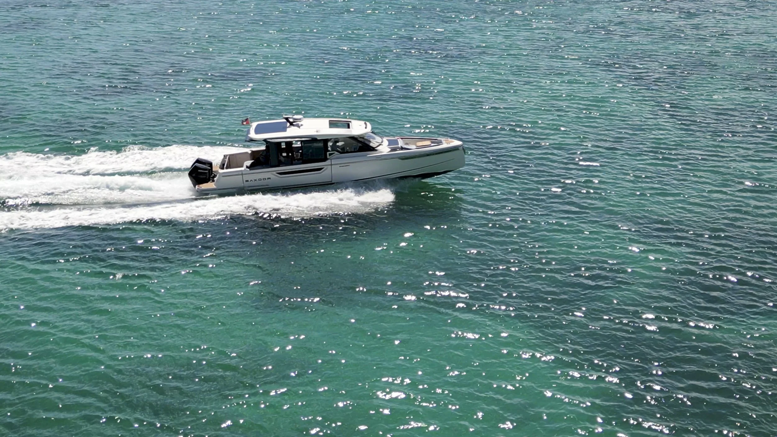 A white motorboat moving across turquoise ocean water, creating a wake.