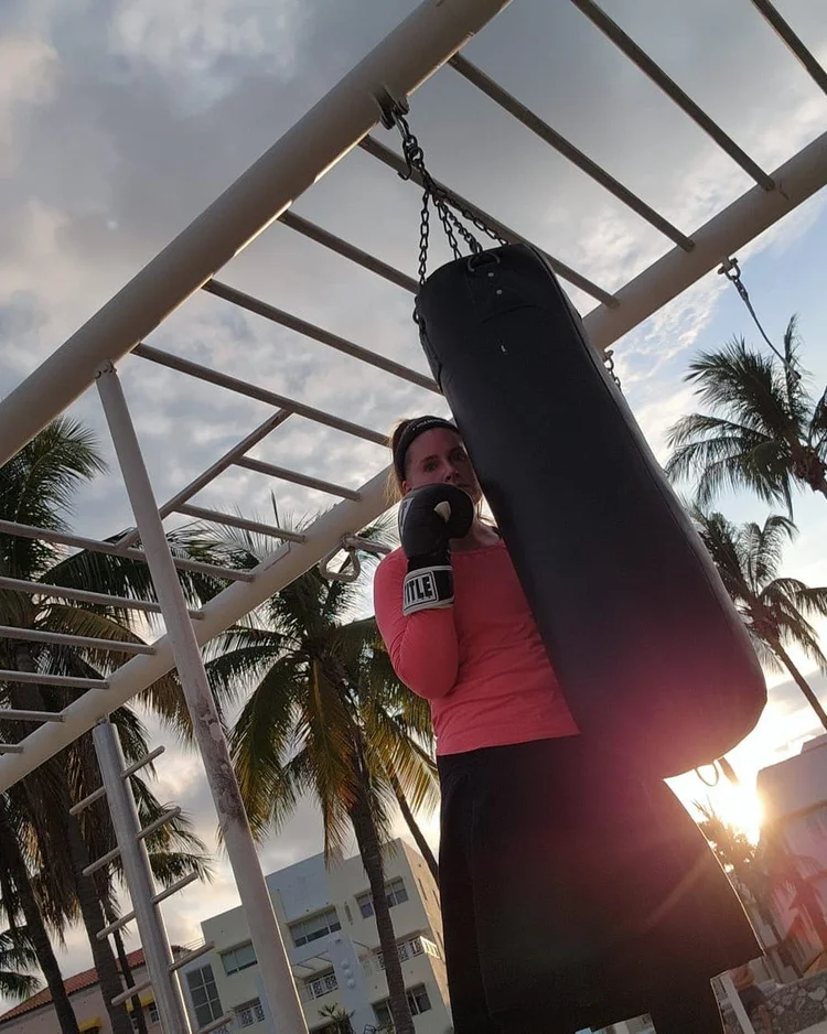 C.P. Handler boxing a heavy bag outdoors at sunset