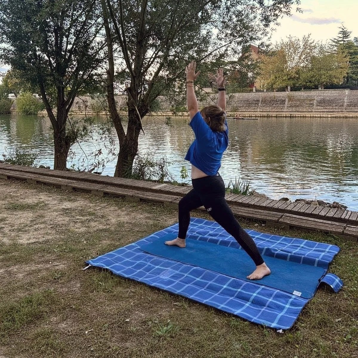 Marion, professeure de yoga et sophrologue, en posture de guerrier au bord de l'eau