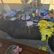 Table with colorful paint, brushes, cups, and art supplies for a messy art project.