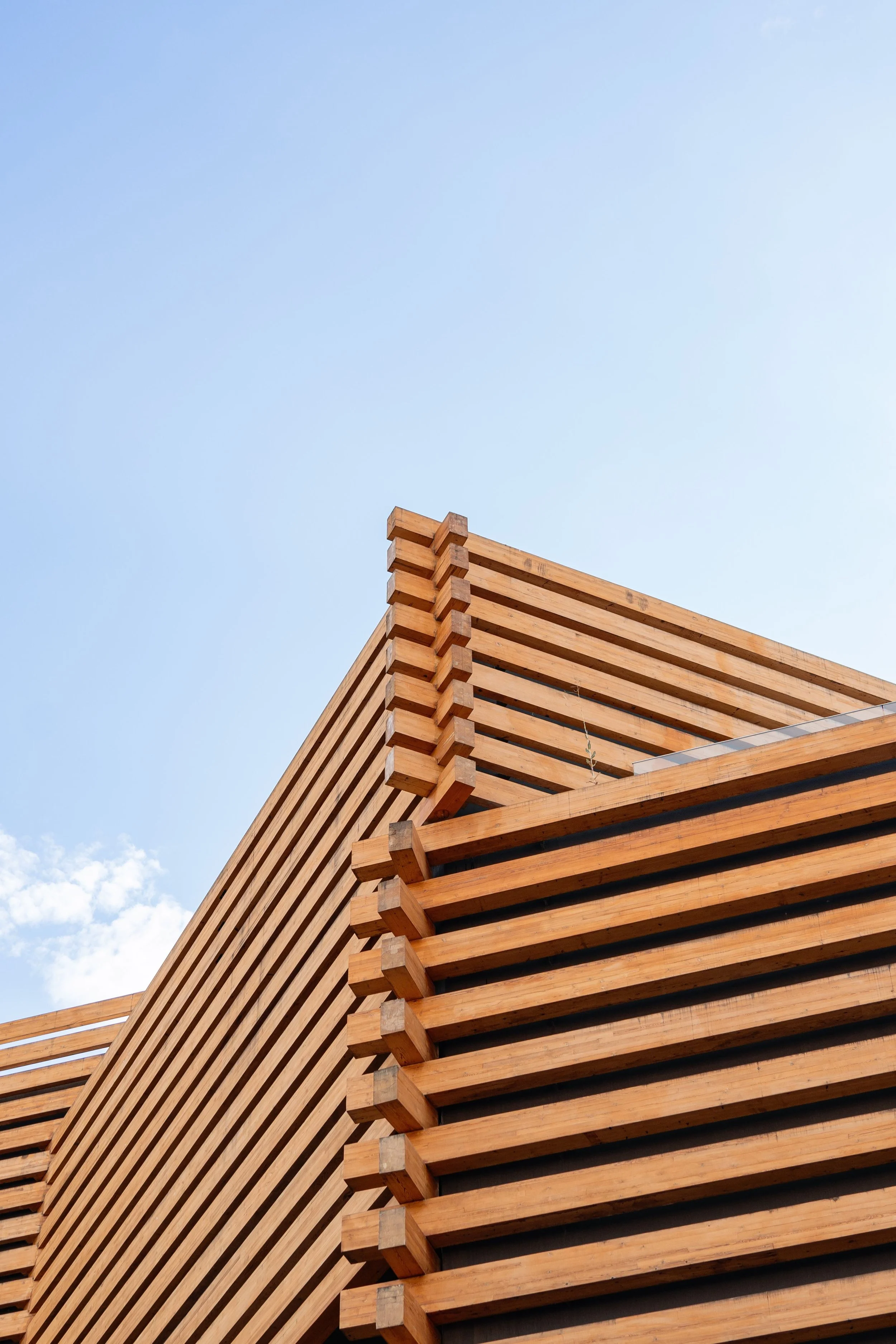 Close-up of a modern building with a wooden slat exterior against a clear blue sky.