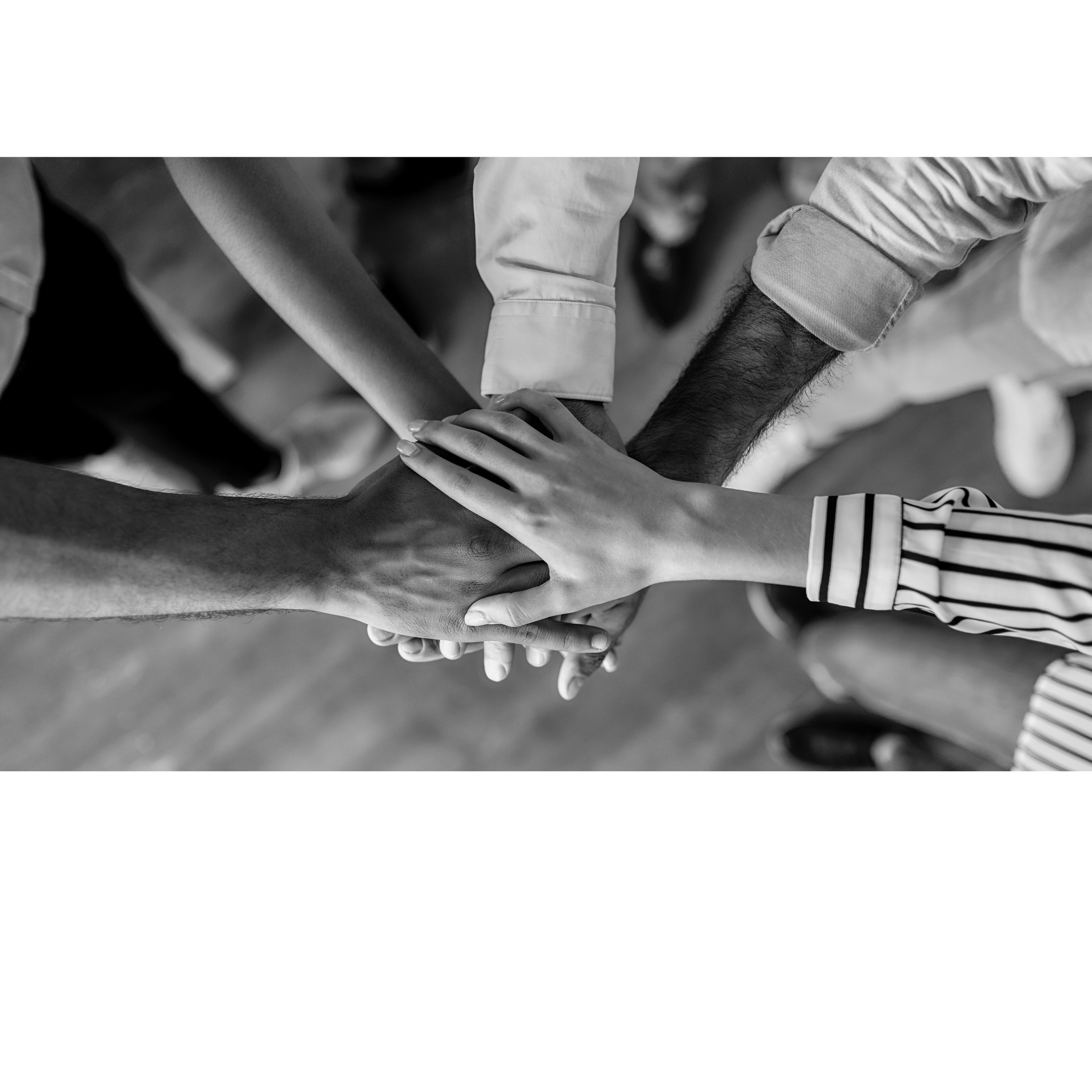 Multiple hands stacked on top of each other, symbolizing teamwork and unity.