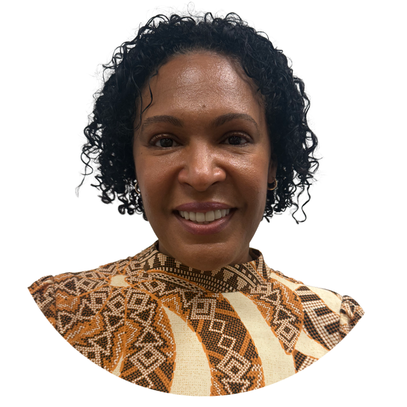 A woman with curly black hair, smiling, wearing an African print patterned top.