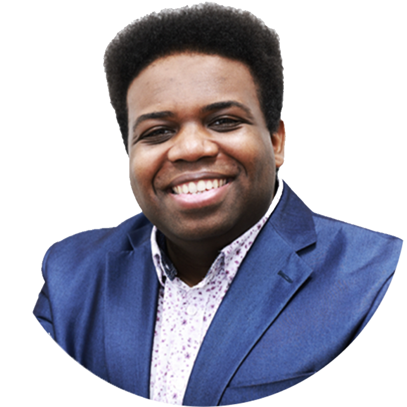 A young man with dark skin and short curly hair, smiling, wearing a blue blazer over a white shirt with small purple patterns, in a professional portrait style.