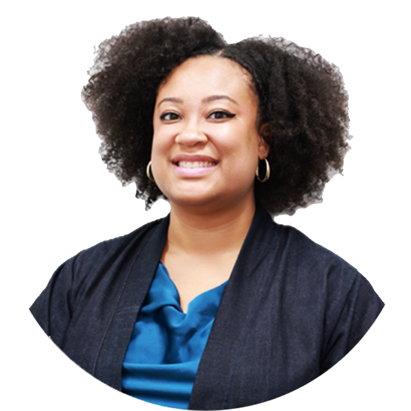 A woman with curly hair smiling, wearing a blue blouse and black blazer.