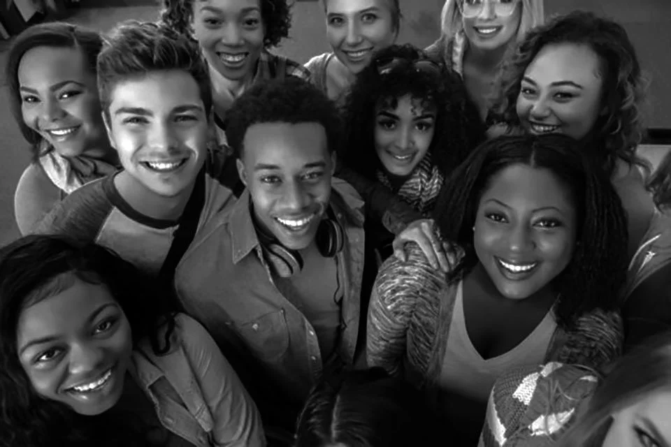 A diverse group of smiling young people taking a selfie together.