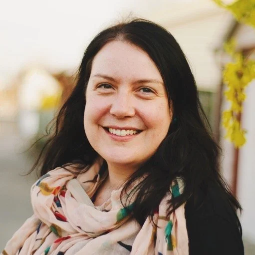 Kathe Rogers is pictured, a woman with long dark hair smiling outdoors, wearing a light-coloured scarf with a floral pattern.