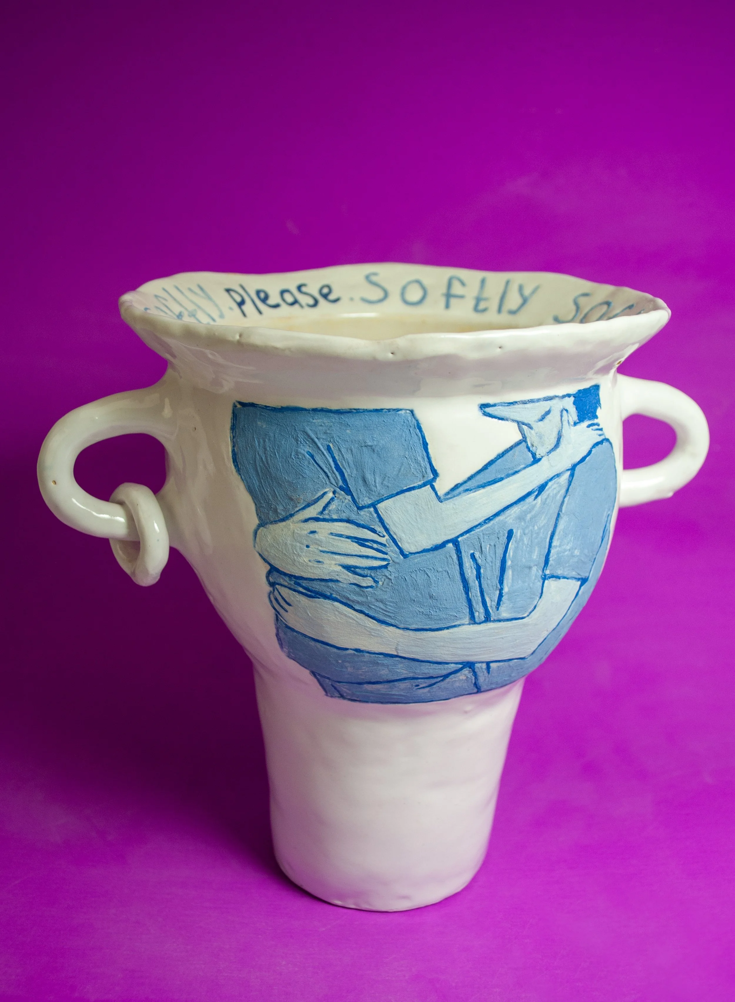 Ceramic mug with blue illustration of a person sitting at a desk and writing, and a handwritten message inside the rim that reads 'Please. Sofly so' against a purple background.