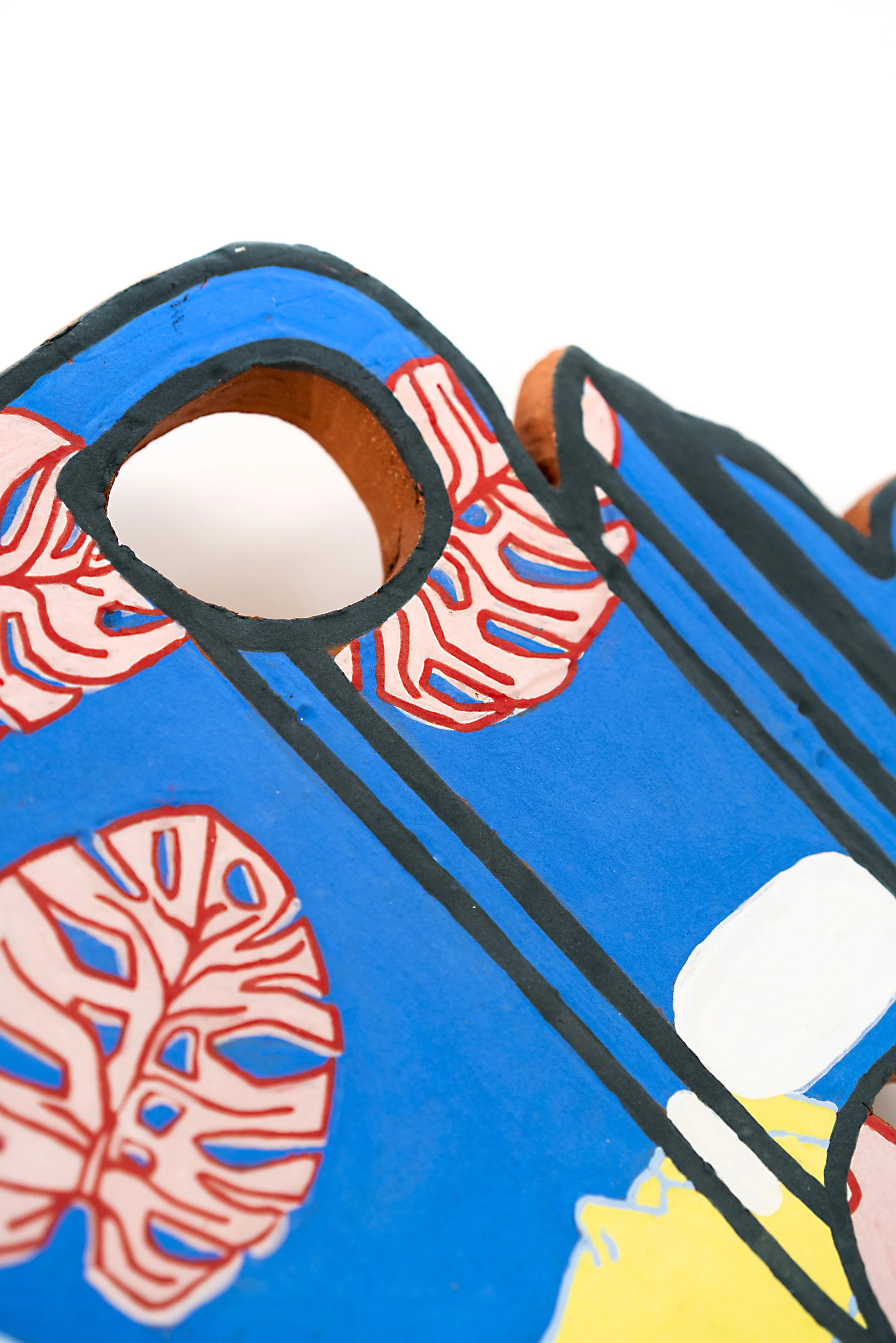Close-up of a colorful, painted wooden object with red, blue, yellow, and black patterns.