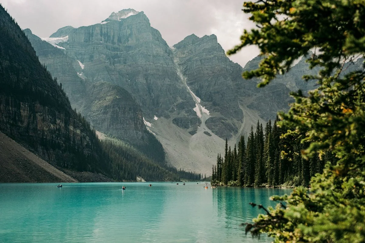 A scenic mountain lake with turquoise water, surrounded by evergreen trees.