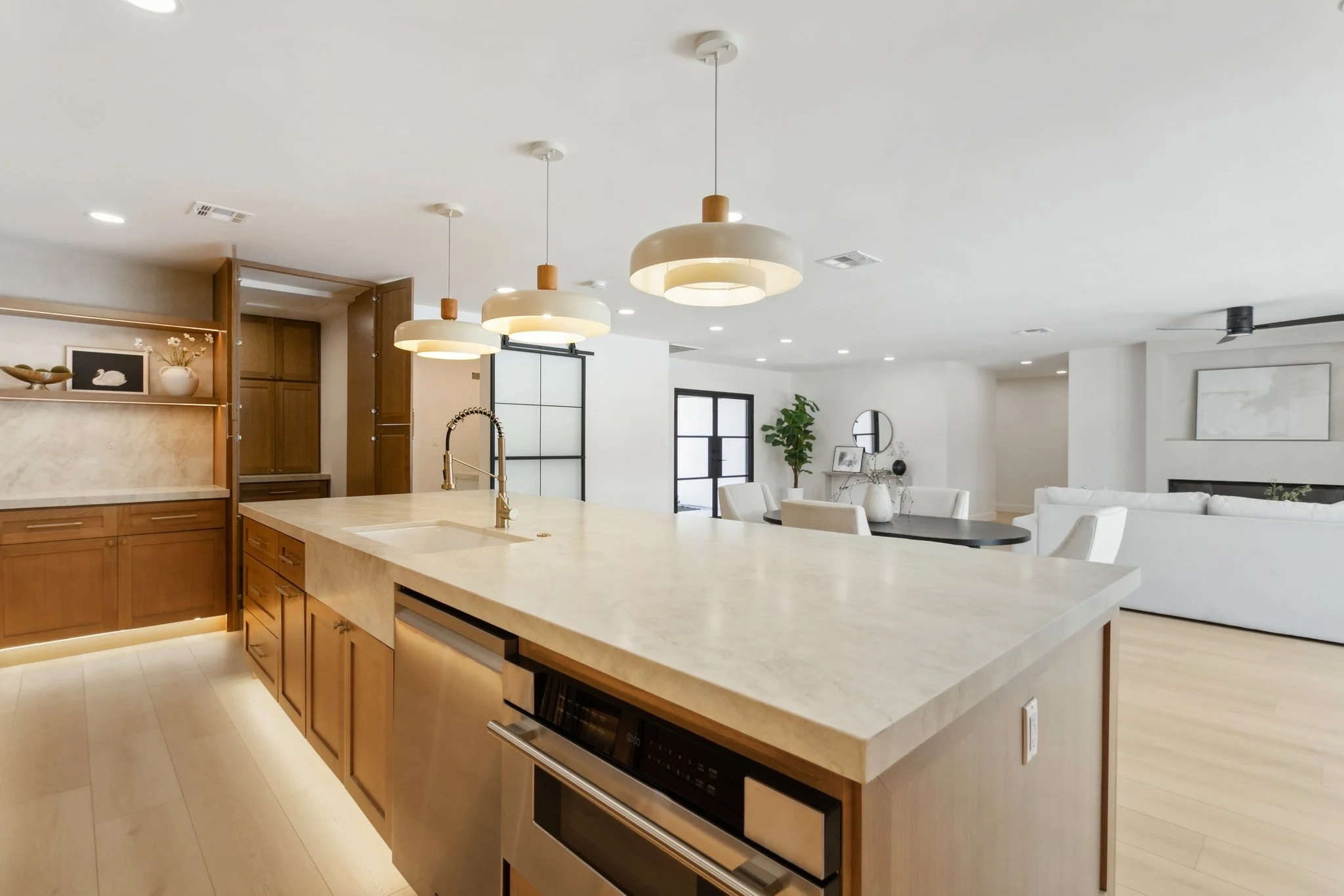 Modern open-concept kitchen and living area with a large island, pendant lighting, and a white sofa.