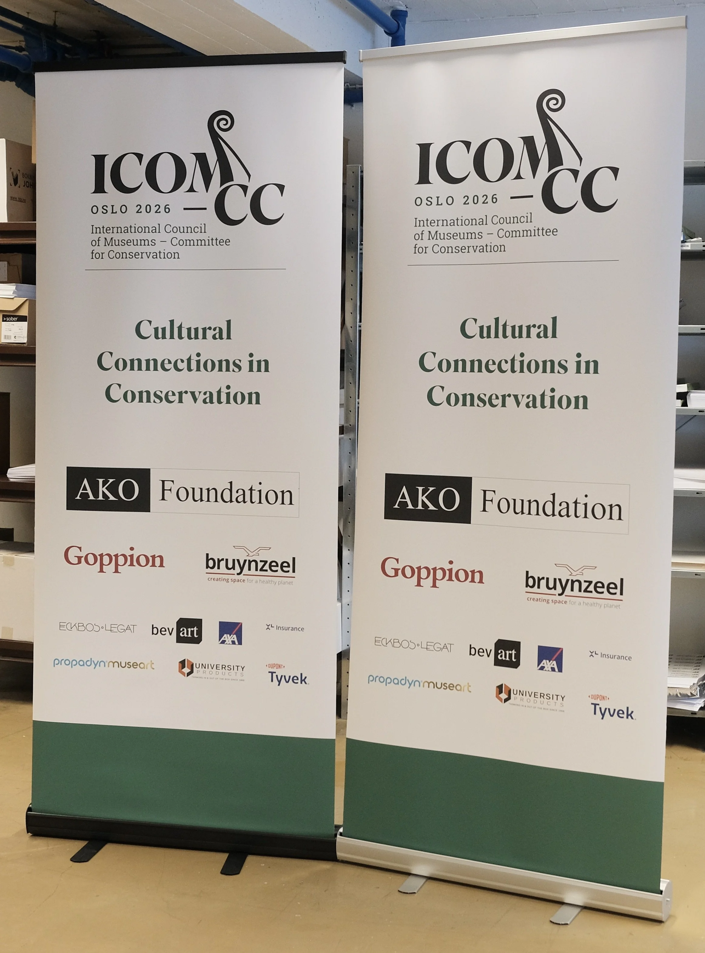 To roll-up bannere for et arrangement i Oslo 2026 med temaet 'Kulturelle forbindelser i bevaring', organisert av International Council of Museums – Committee for Conservation. Båndene viser logoer og navn på sponsorer som Goppion, Bruynzeel, AXA, Tyv