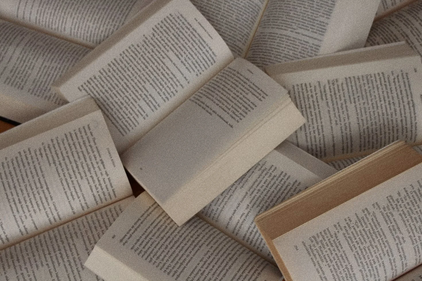 Multiple open books scattered on a surface, with visible pages and text.