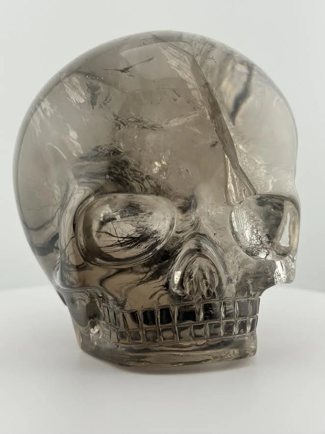 A crystalline carving of a margical child skull with tourmaline inclusions inside.
