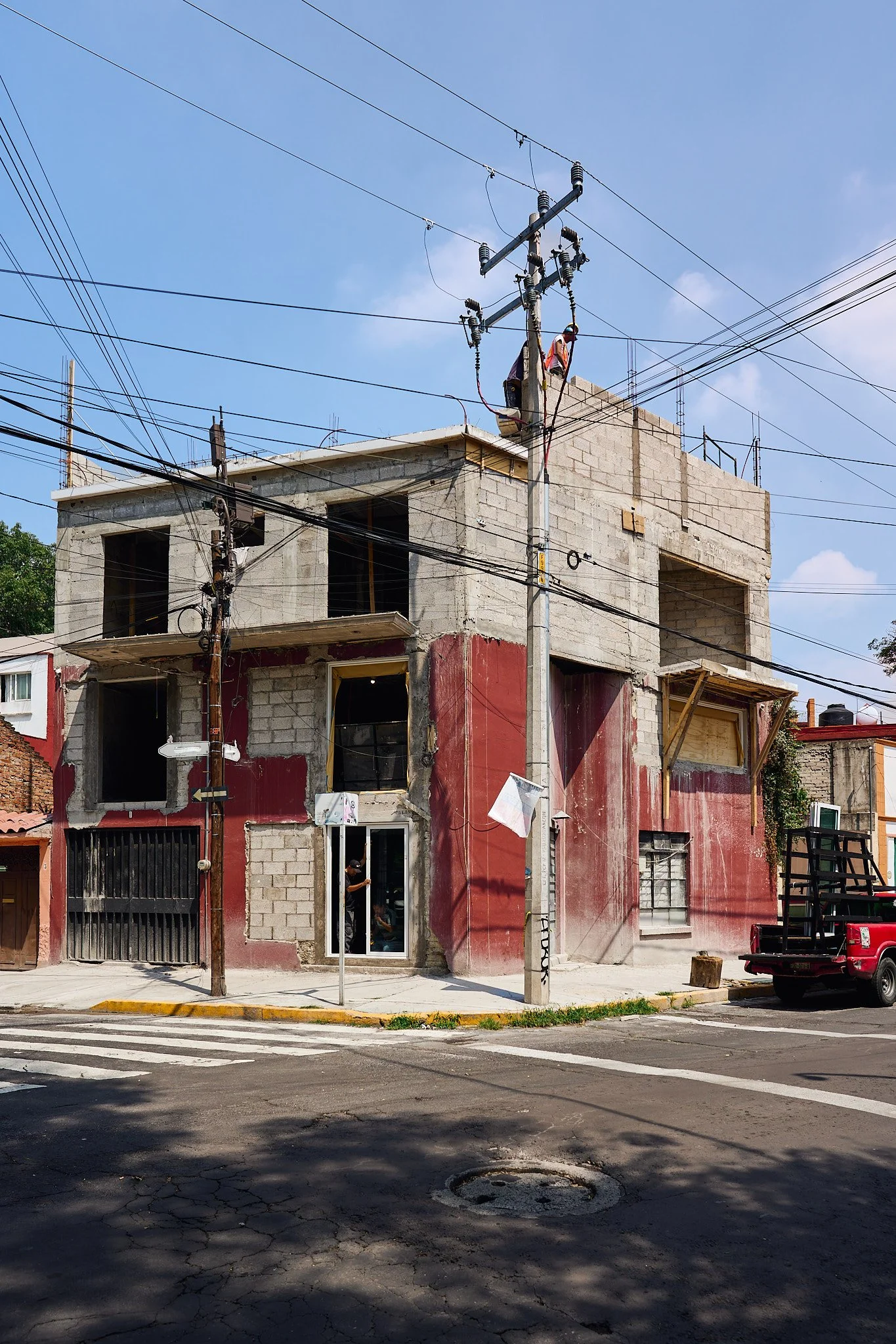 Edificio en construcción en una esquina de la calle con cables eléctricos y un semáforo en el cruce