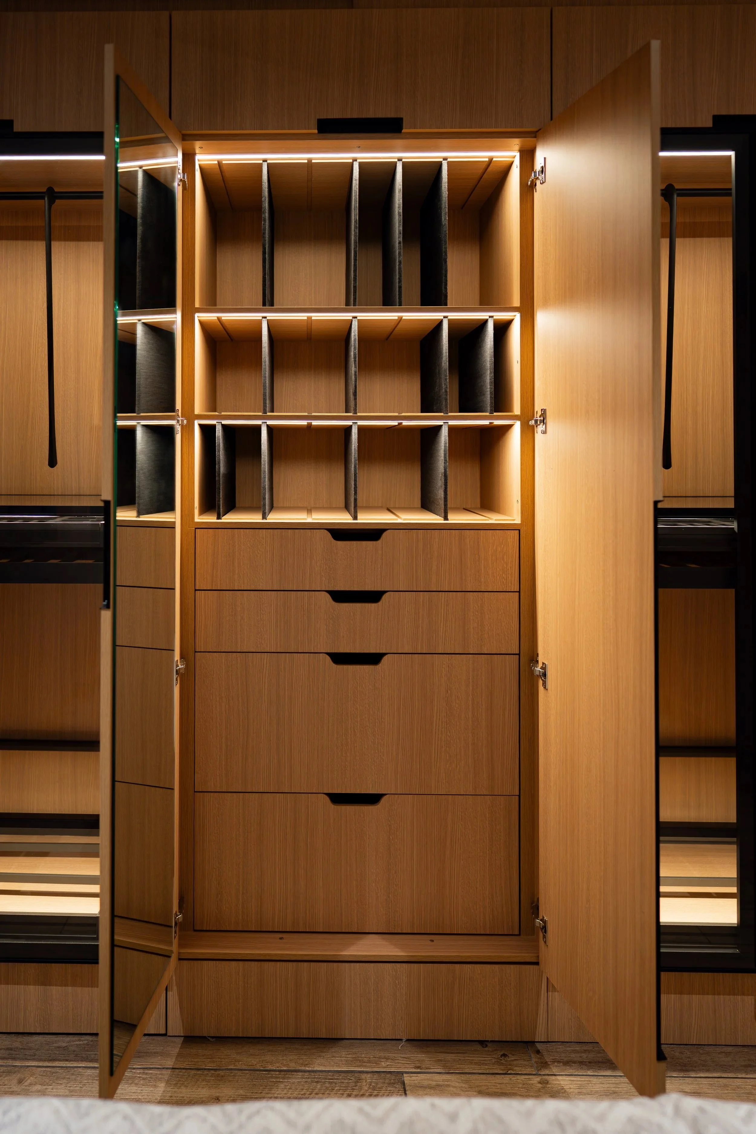 Armario de madera con puertas abiertas, mostrando compartimentos con divisores y cajones en un ambiente moderno.