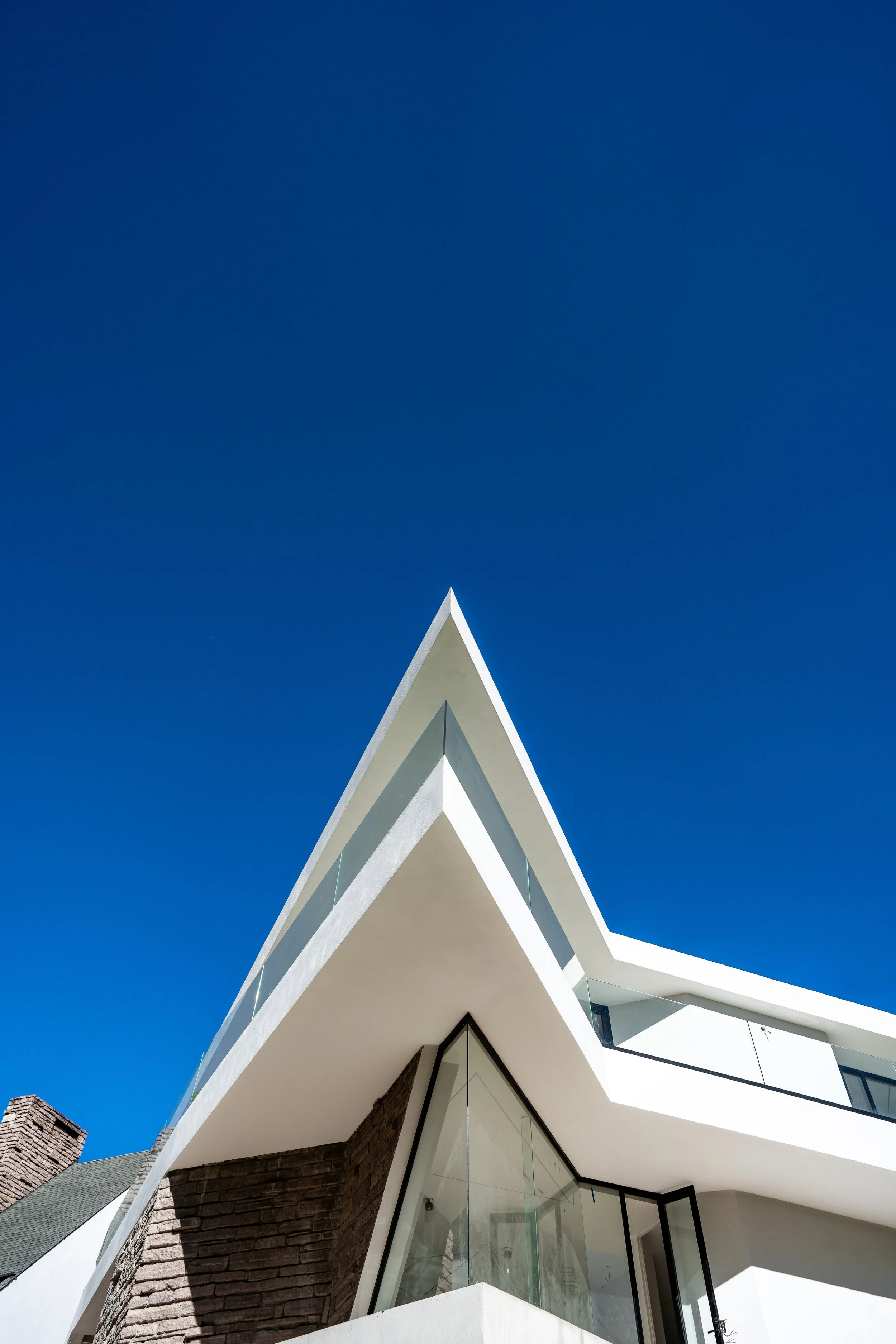 Vista frontal de un edificio moderno con techos angulares blancos y ventanas de vidrio, bajo un cielo claro y azul.