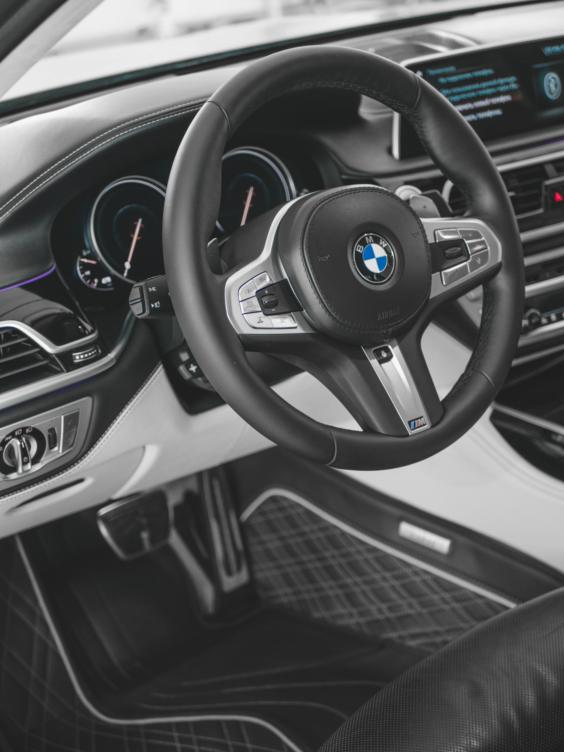 Interiør av en BMW bil med fokus på ratt, instrumentpanel og dashbord.