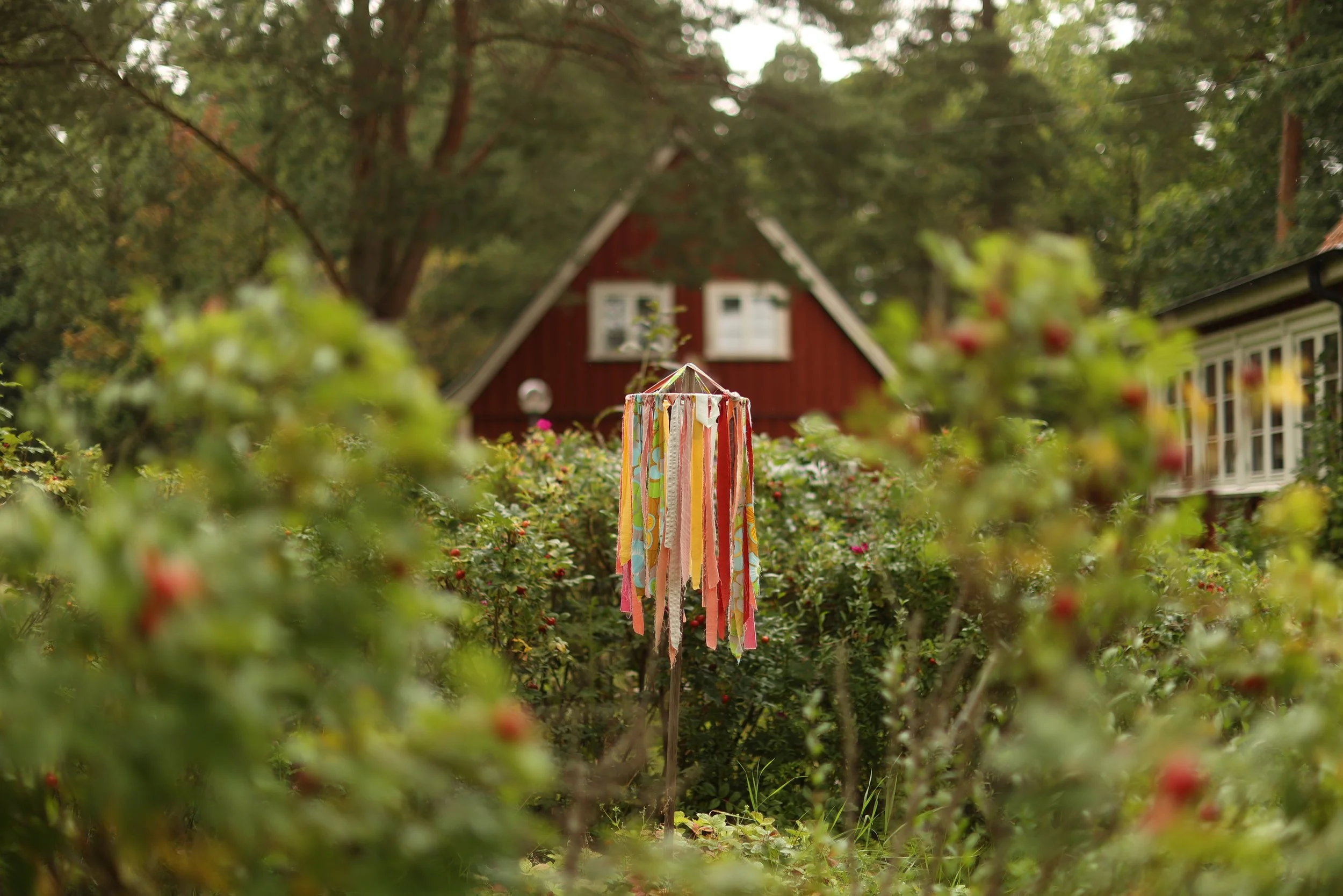 Färgglad konst i trädgård med röda hus och gröna träd.