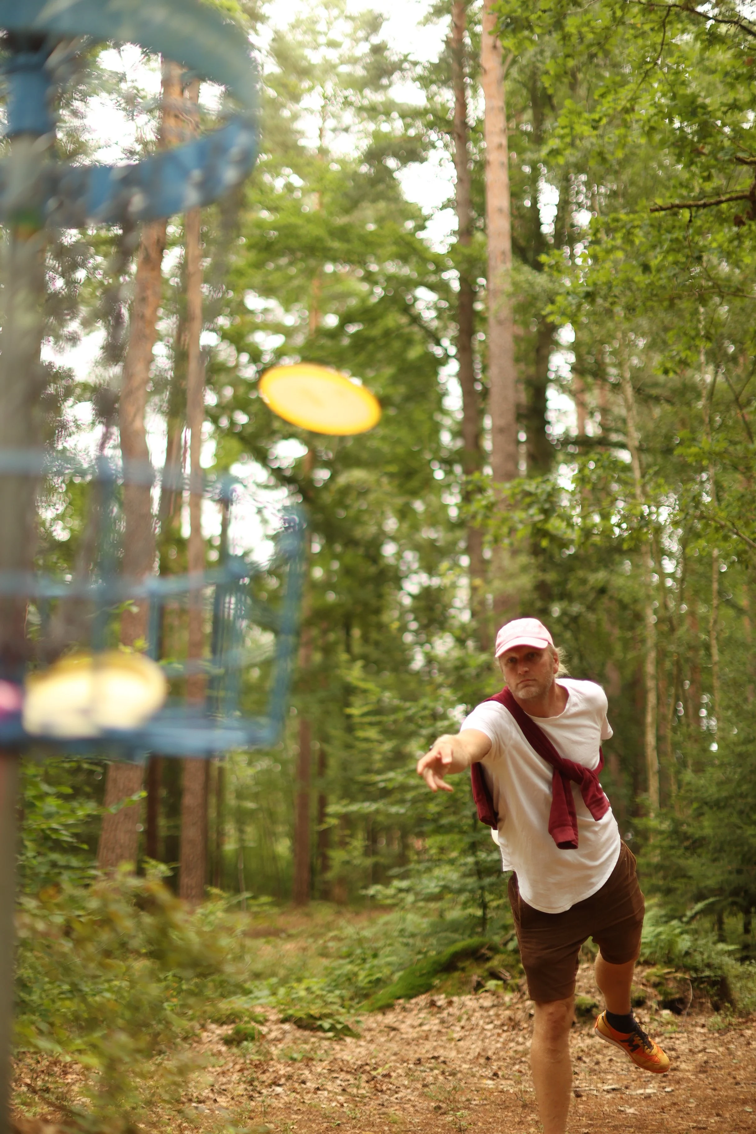 Man i skog som kastar disc golf, med ett nät och frisbee i förgrunden