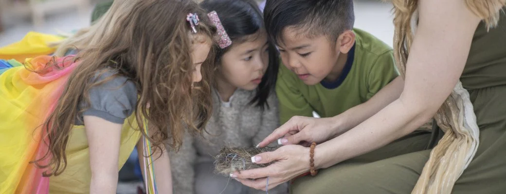 A woman showing three children a clump of hair or fur.