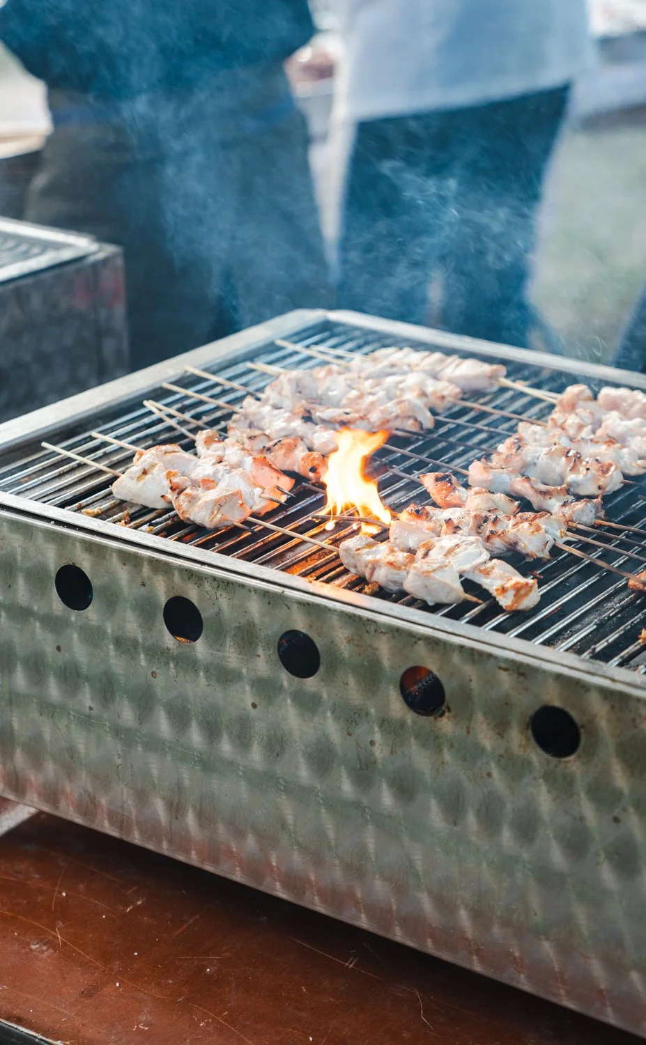 Grill med kyllingspyd over åpen flamme