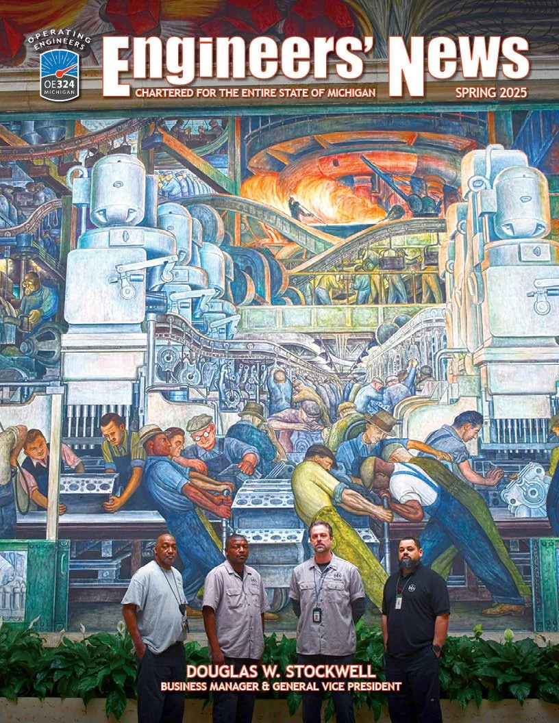 A mural depicting an industrial factory scene with workers operating machinery and assembly lines, with vibrant colors and detailed imagery. Four men standing in front of the mural.
