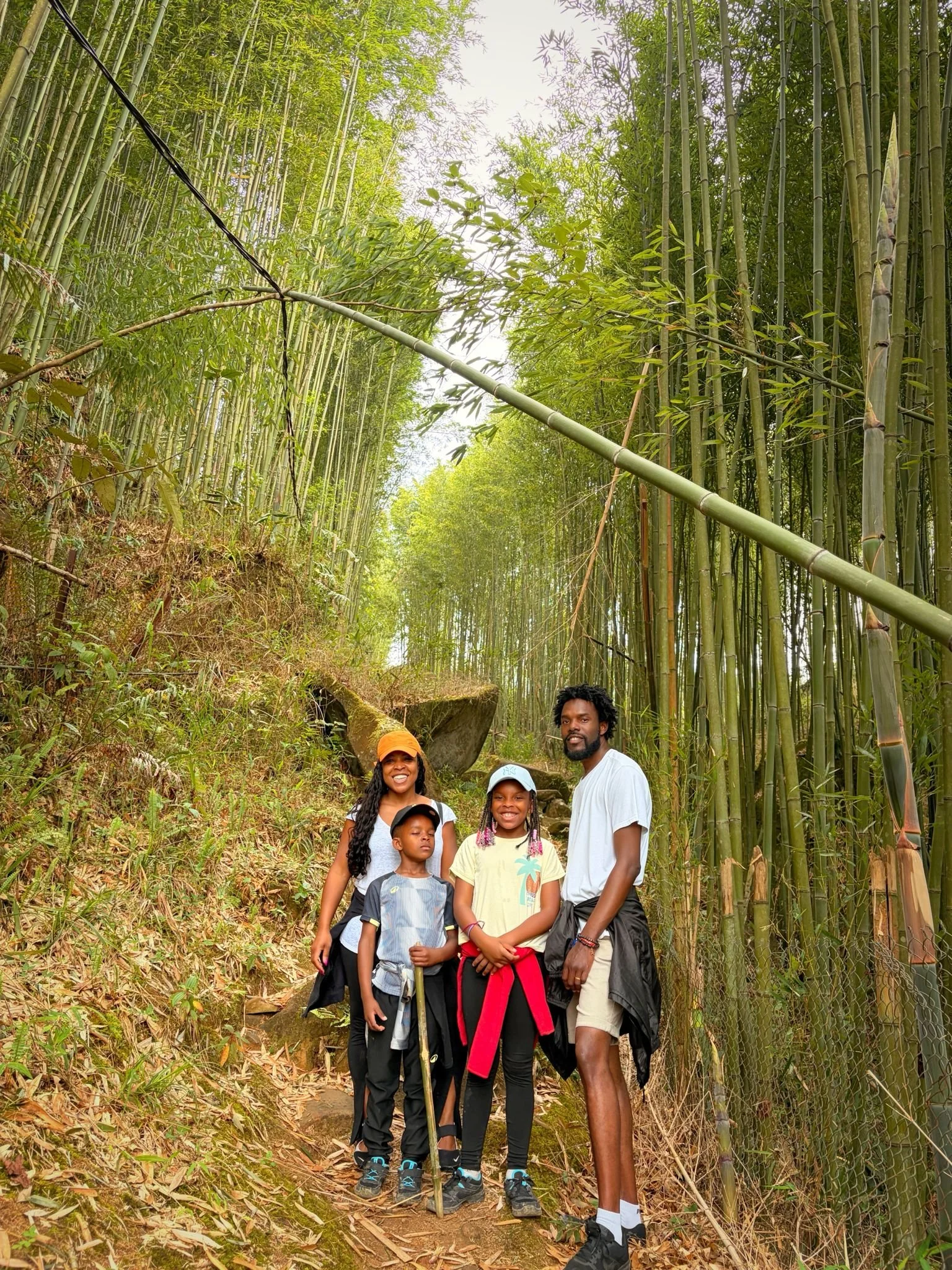 groupe de cinq personnes, un homme, une femme et trois enfants, posant dans une forêt de bambous