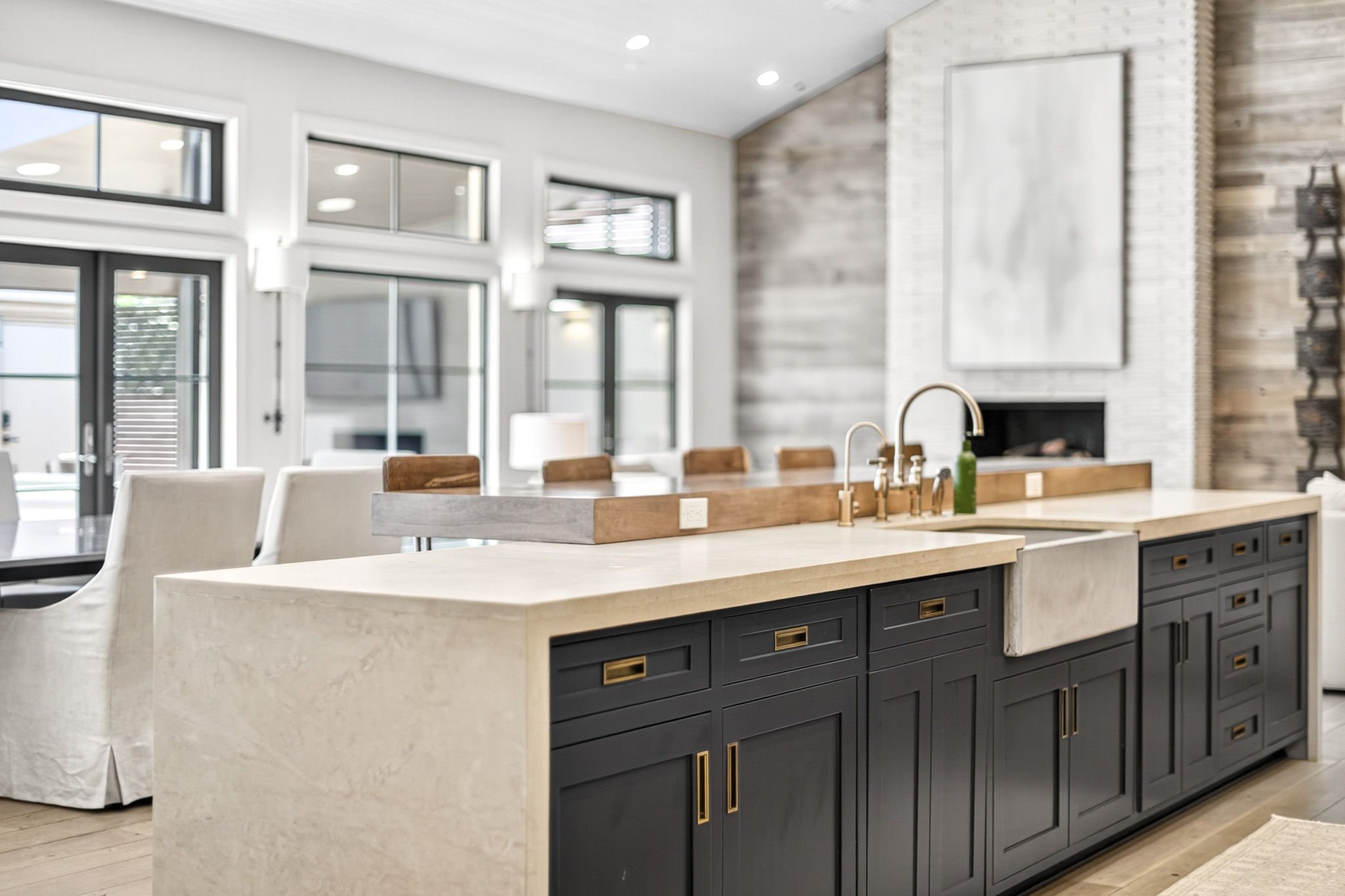 Modern kitchen with white countertops, dark cabinetry, and large windows.
