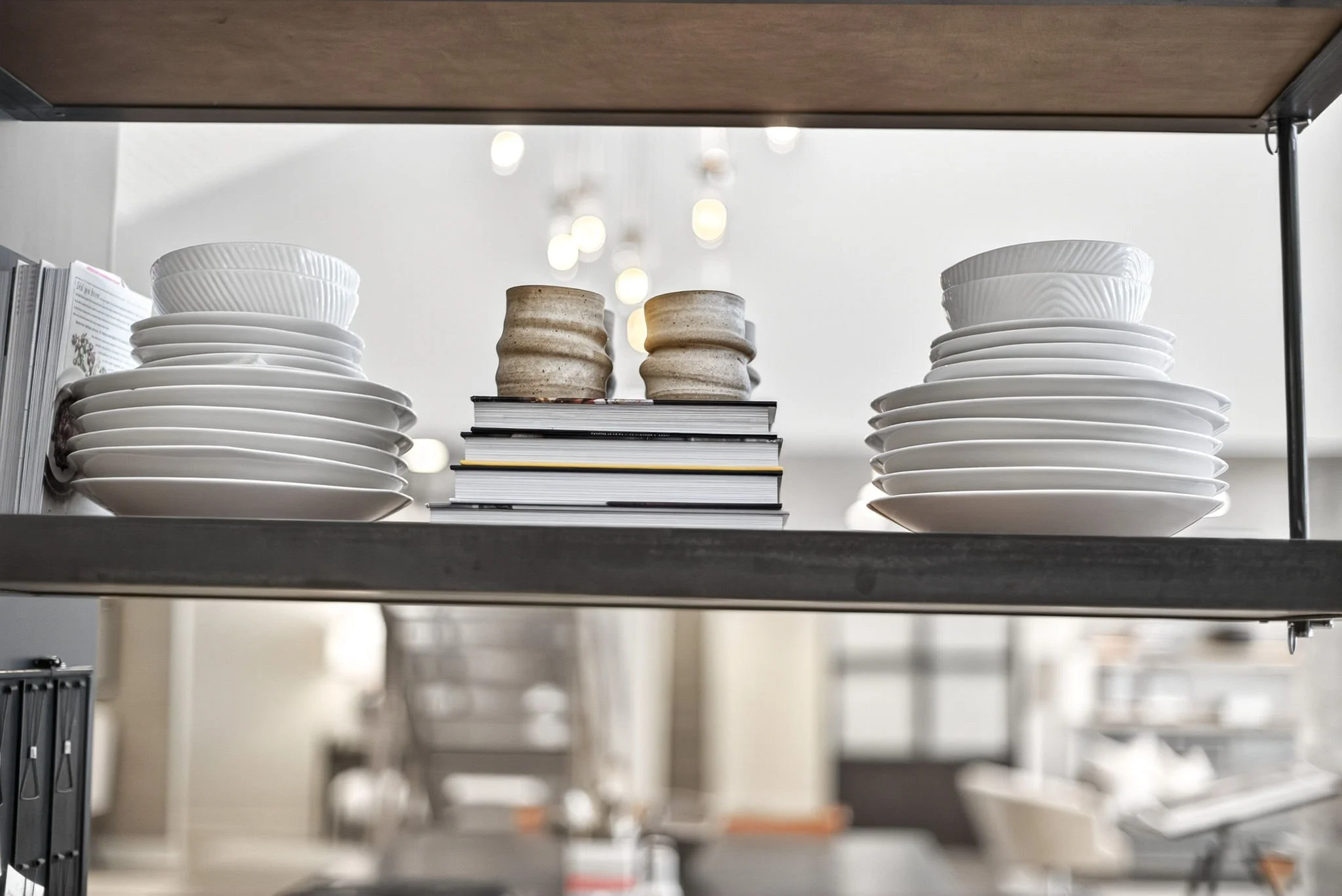 Shelves with stacks of white plates, bowls, and ceramic cups in a kitchen or pantry.
