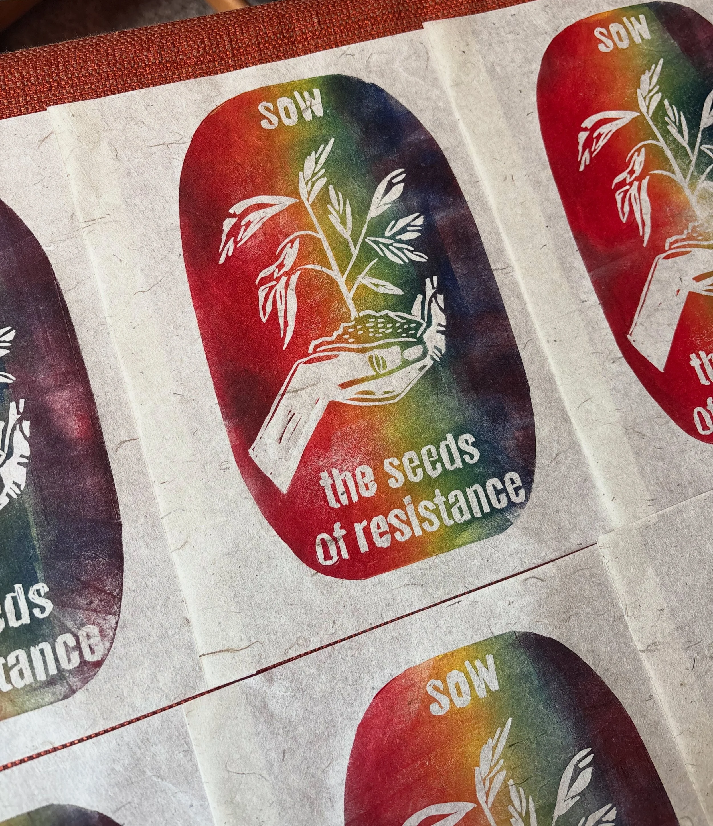 Rainbow-colored logo featuring a hand holding a small plant with leaves, the word 'SOW' at the top, and the hashtag '#theSeedsOfResistances' at the bottom.