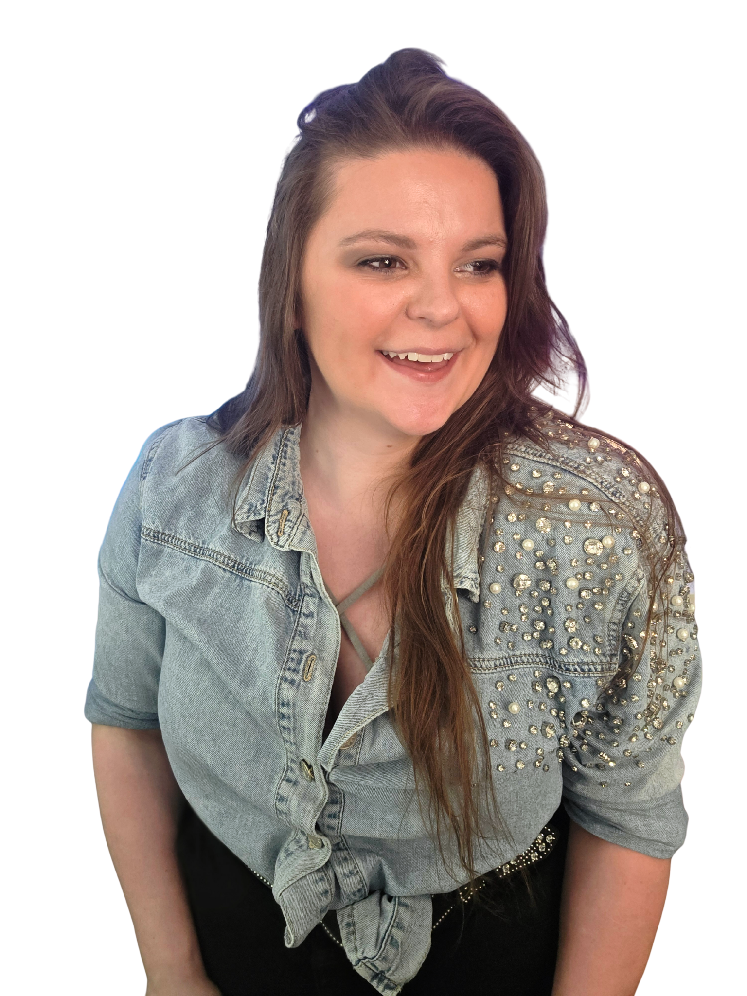 Close-up of a woman with long reddish-brown hair, wearing a denim jacket with pearl embellishments on the shoulders and a black top. She is smiling and looking slightly to the side.