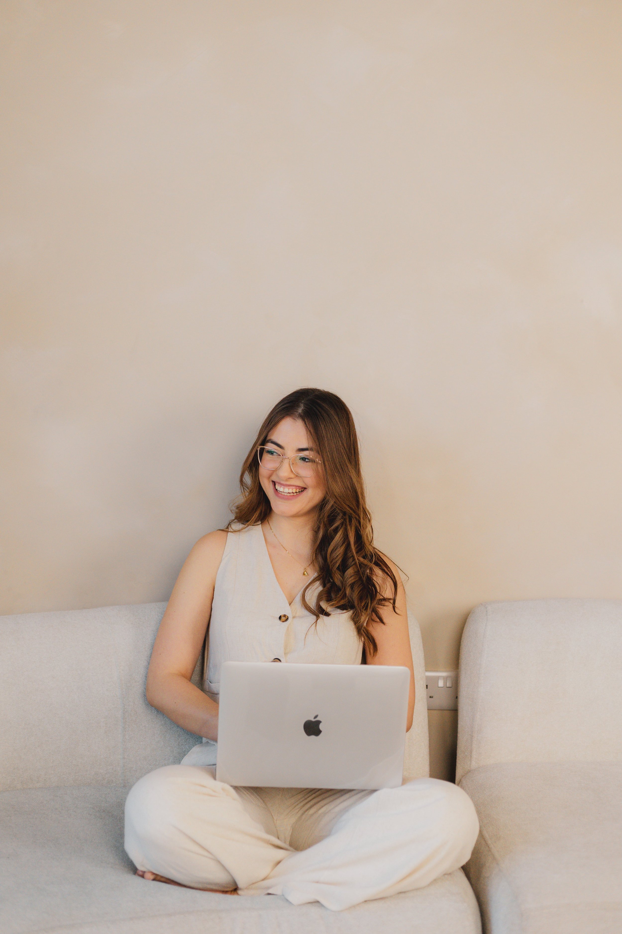 smiling at laptop, teaching how to sell Notion templates and digital products
