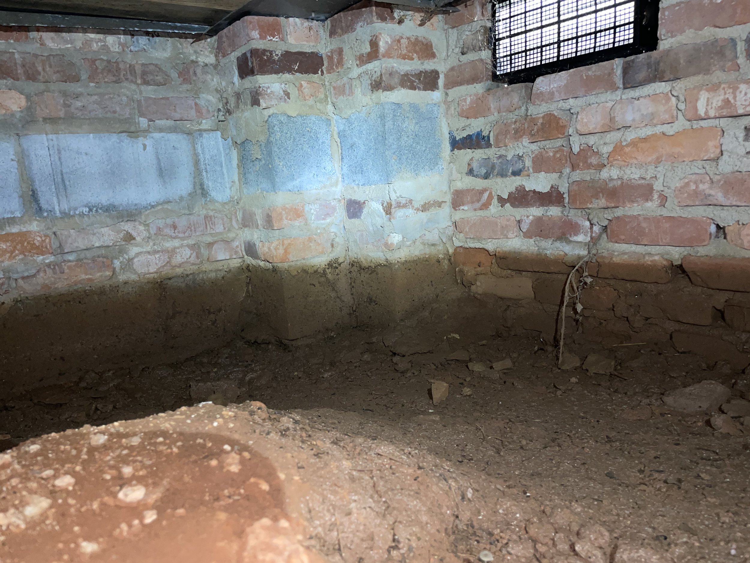 Denver crawl space with exposed soil, missing vapor barrier and signs of past flooding along the foundation walls