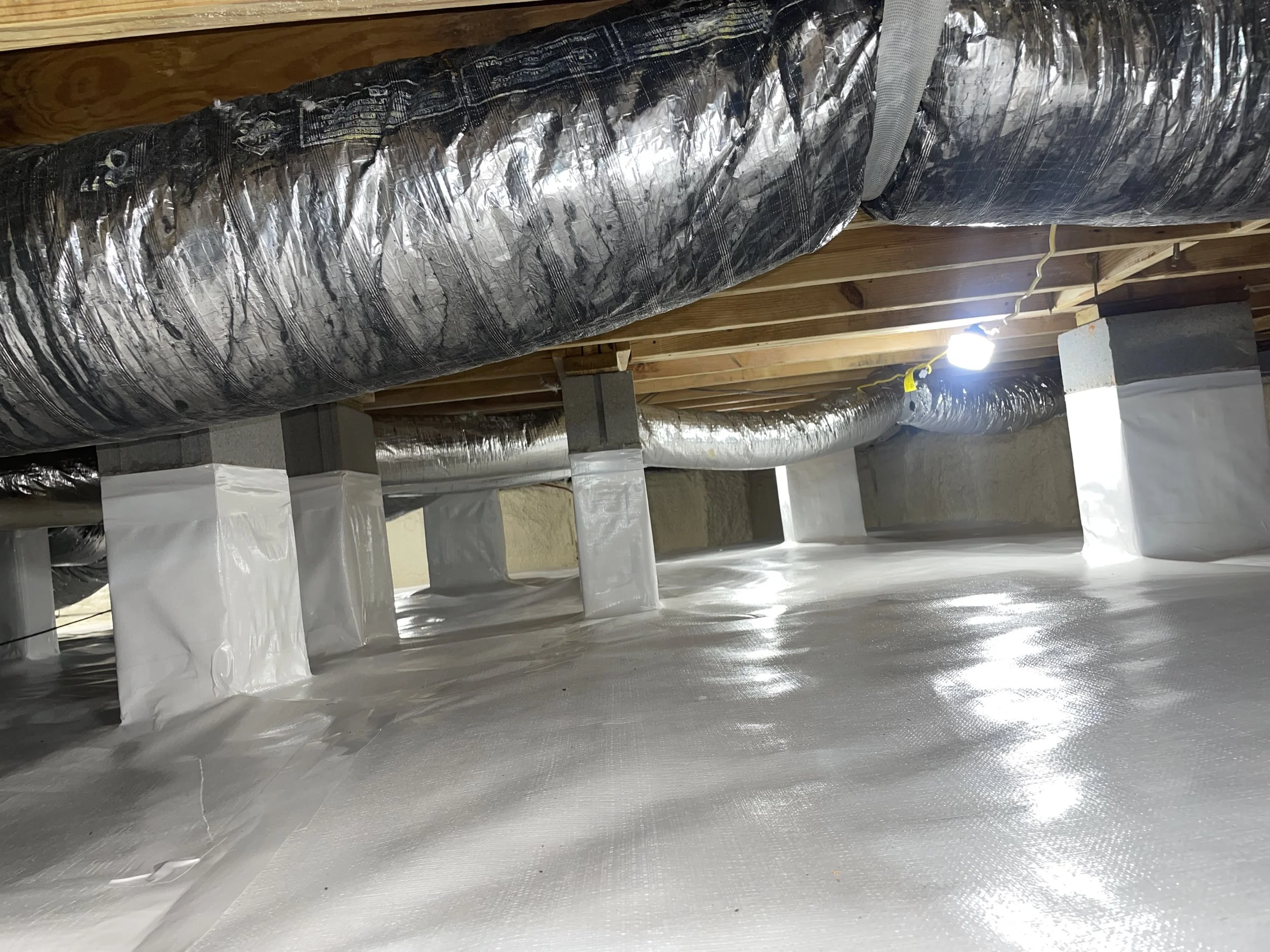 Full crawl space encapsulation with a sealed vapor barrier across the floor, wrapped support piers and sealed foundation walls