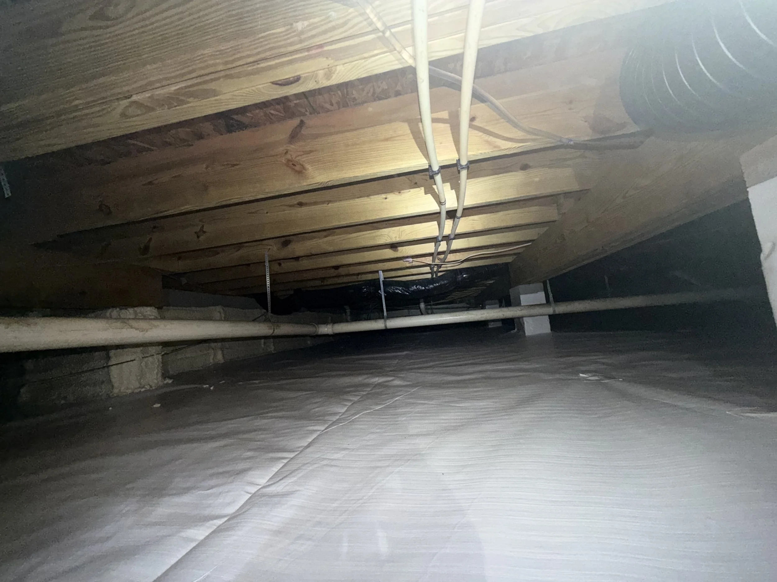 Clean, debris-free crawl space with a new encapsulation liner, wrapped foundation walls and piers, spray-foam insulation and exposed mold-remediated floor joists.