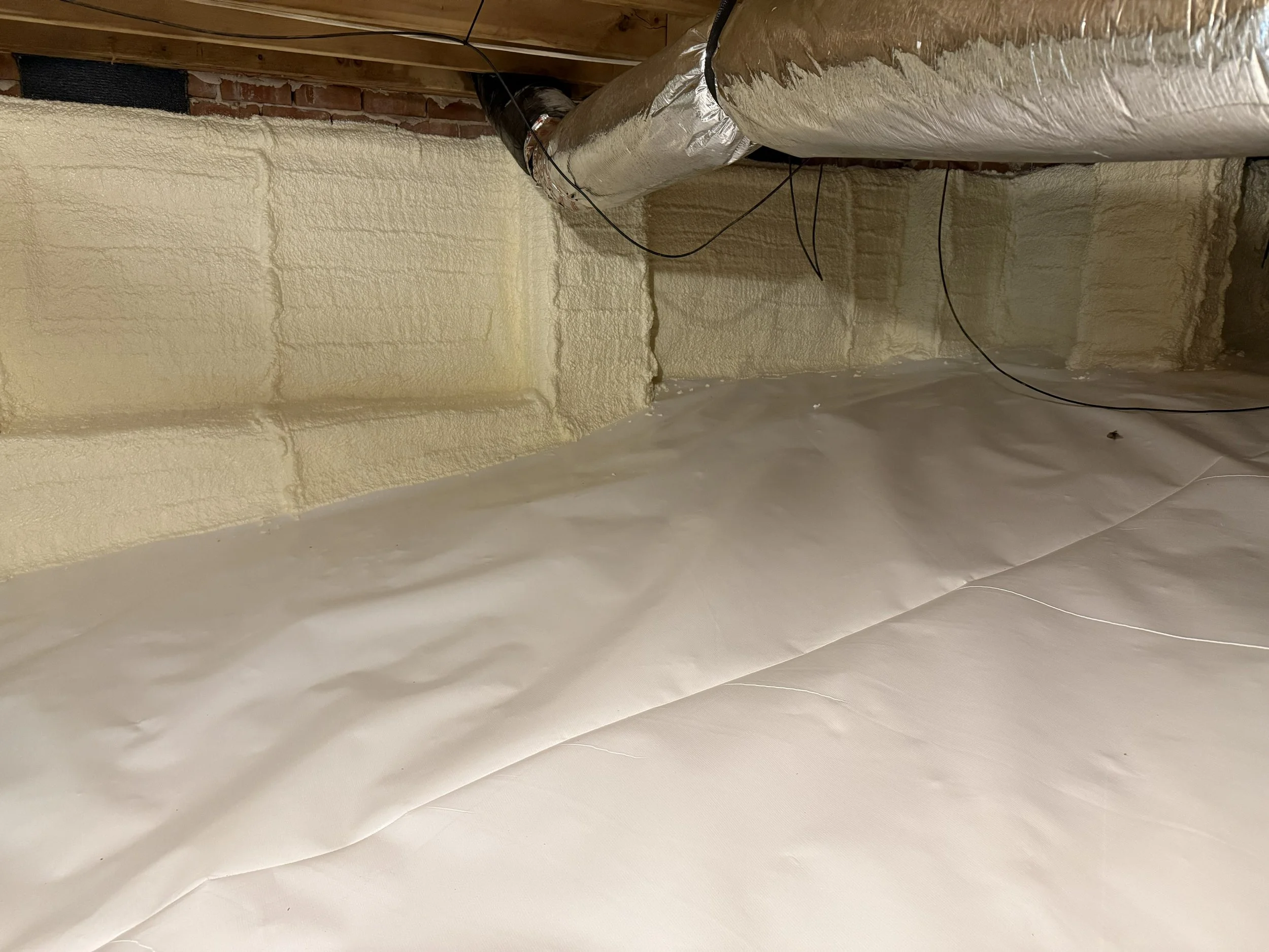Encapsulated crawls space with new vapor barrier, wrapped walls, and spray foam insulation.