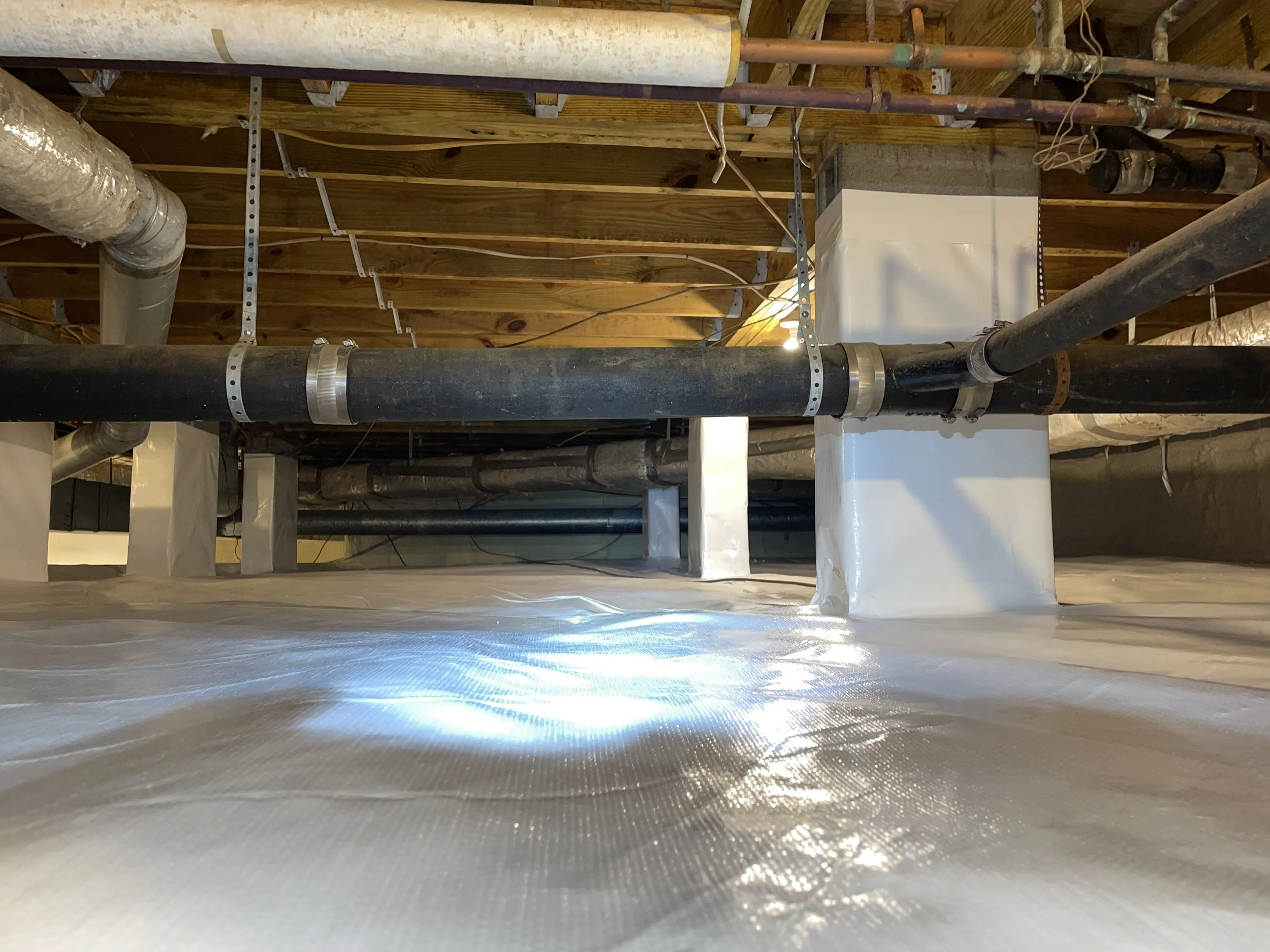 Encapsulated crawl space in Cornelius, NC with a sealed floor liner, wrapped piers and exposed wood framing