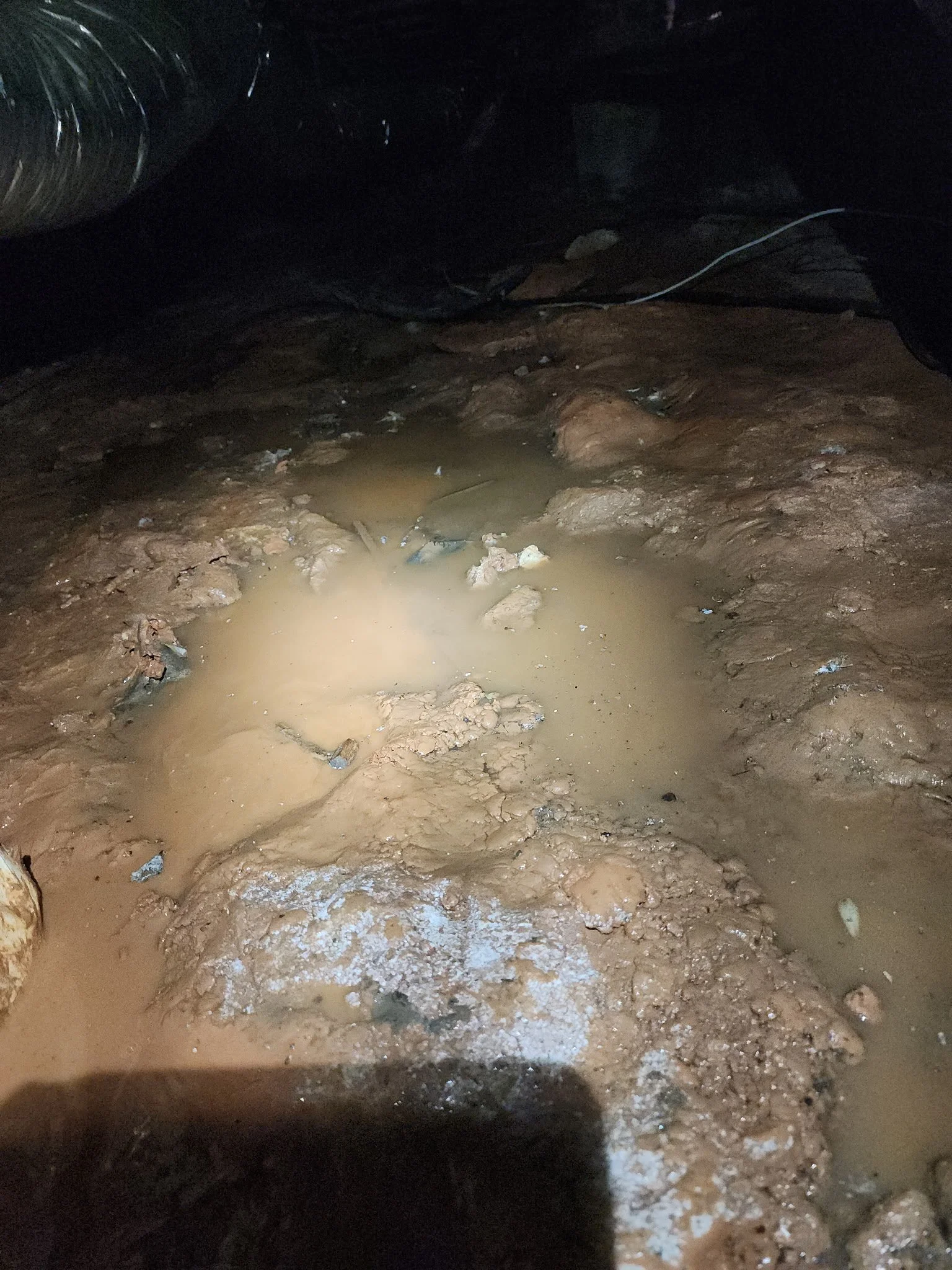 Standing water and saturated soil inside a crawl space requiring drainage