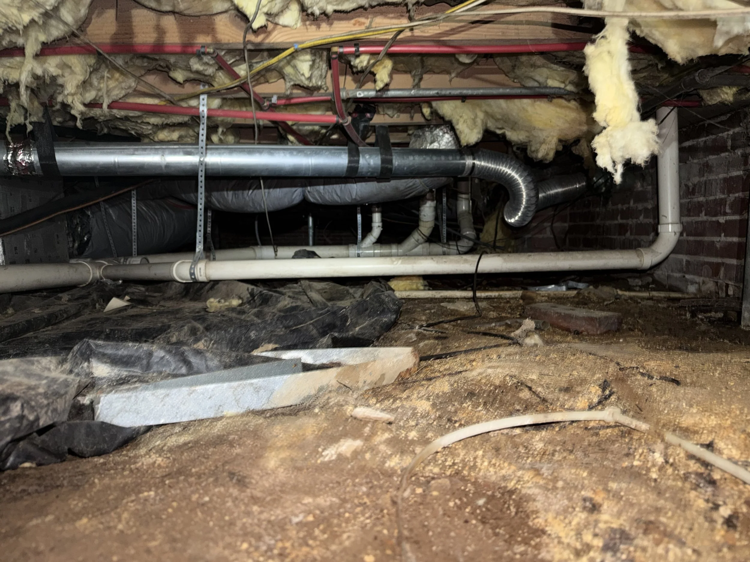 Exposed soil, deteriorated vapor barrier and falling insulation in a Gastonia, NC crawl space