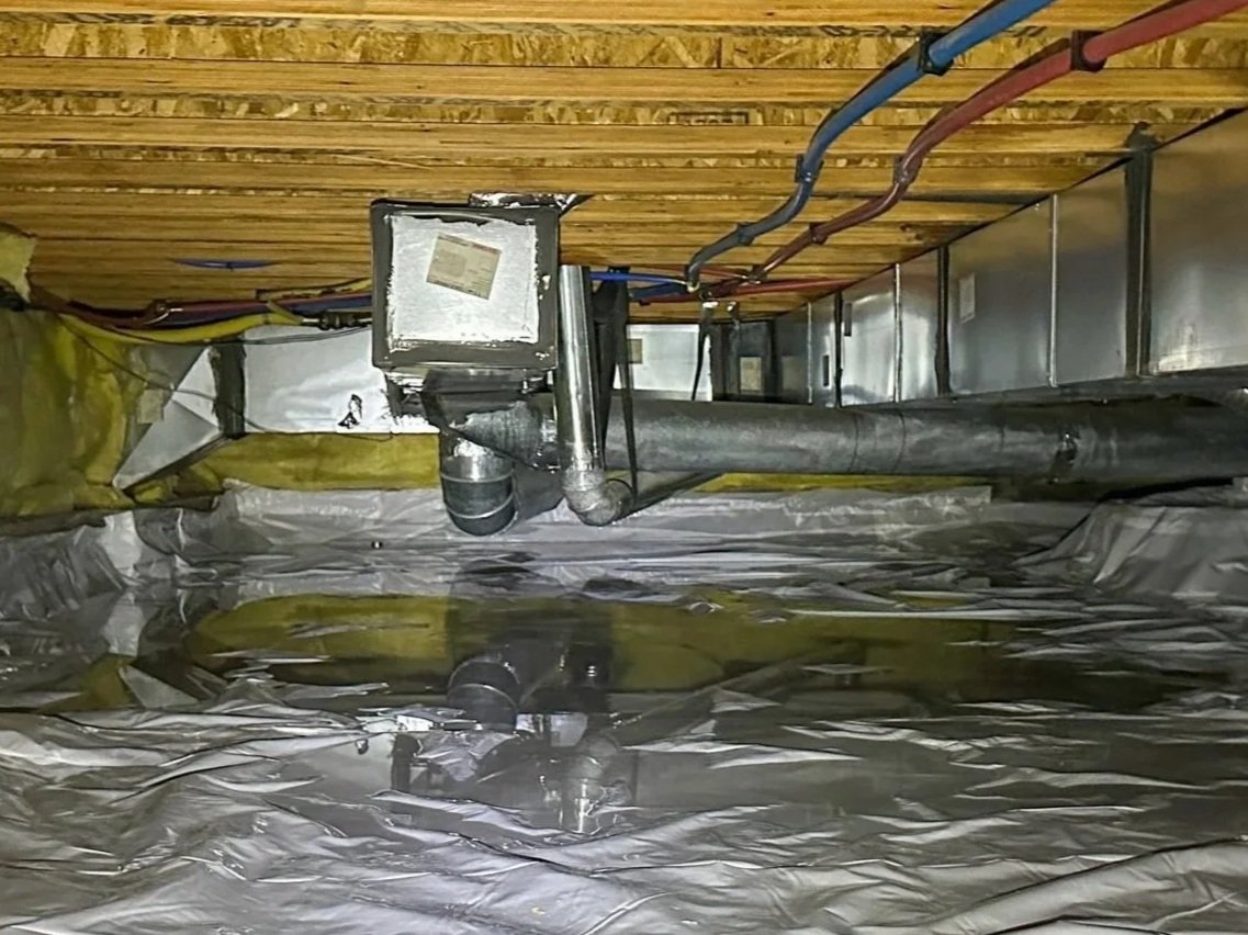 Standing water on top of a crawl space vapor barrier beneath HVAC ductwork in a Huntersville home